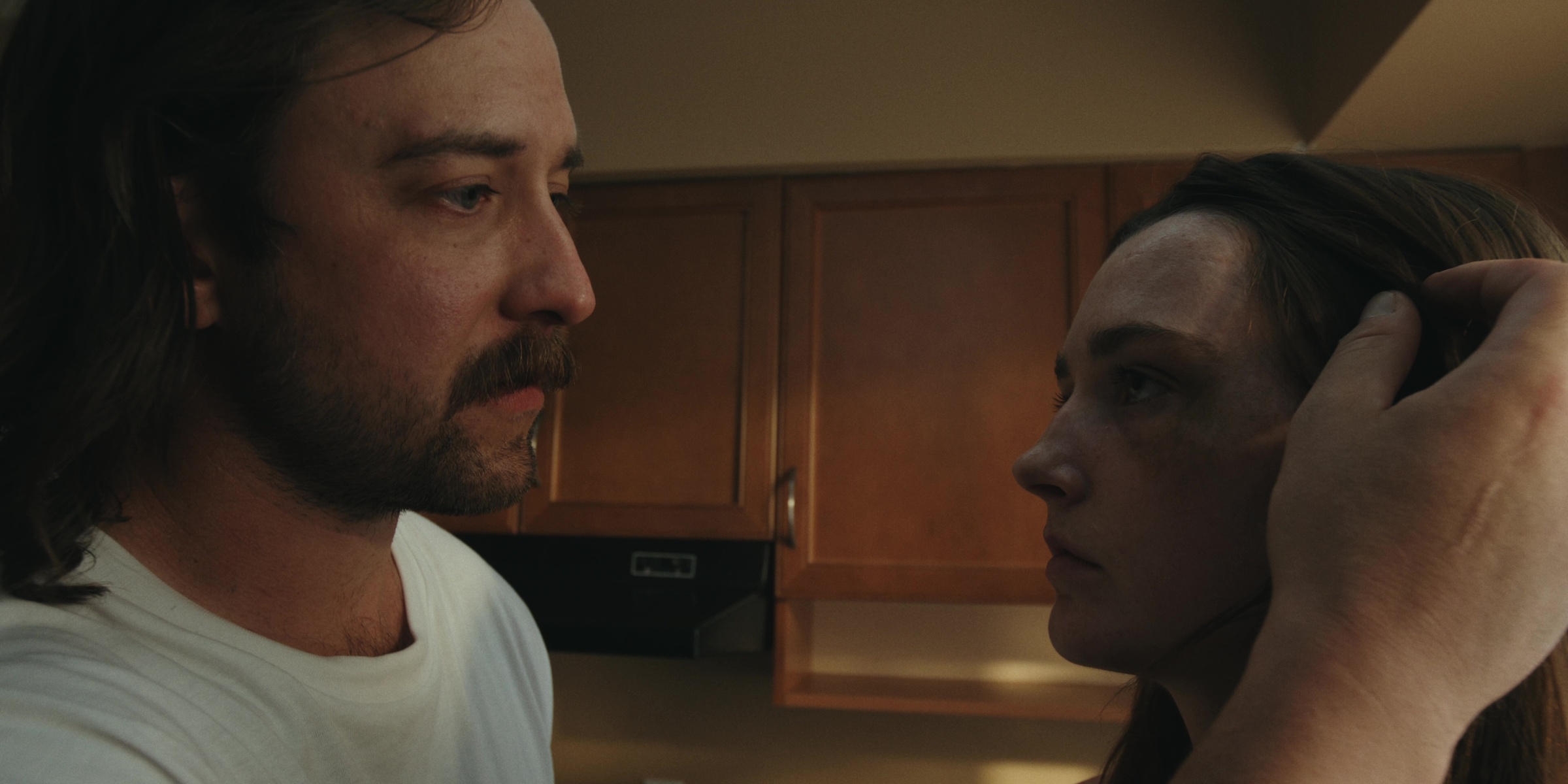 A man touches a woman’s hair in a kitchen — Bottom of the bottle