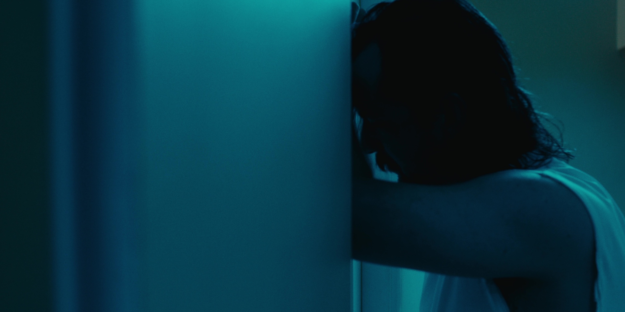 A man leans against a doorway in blue light — Bottom of the bottle