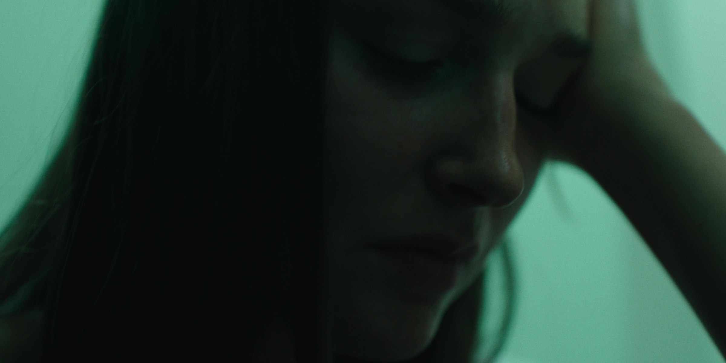 Close-up of a woman holding her head in green light — Bottom of the bottle