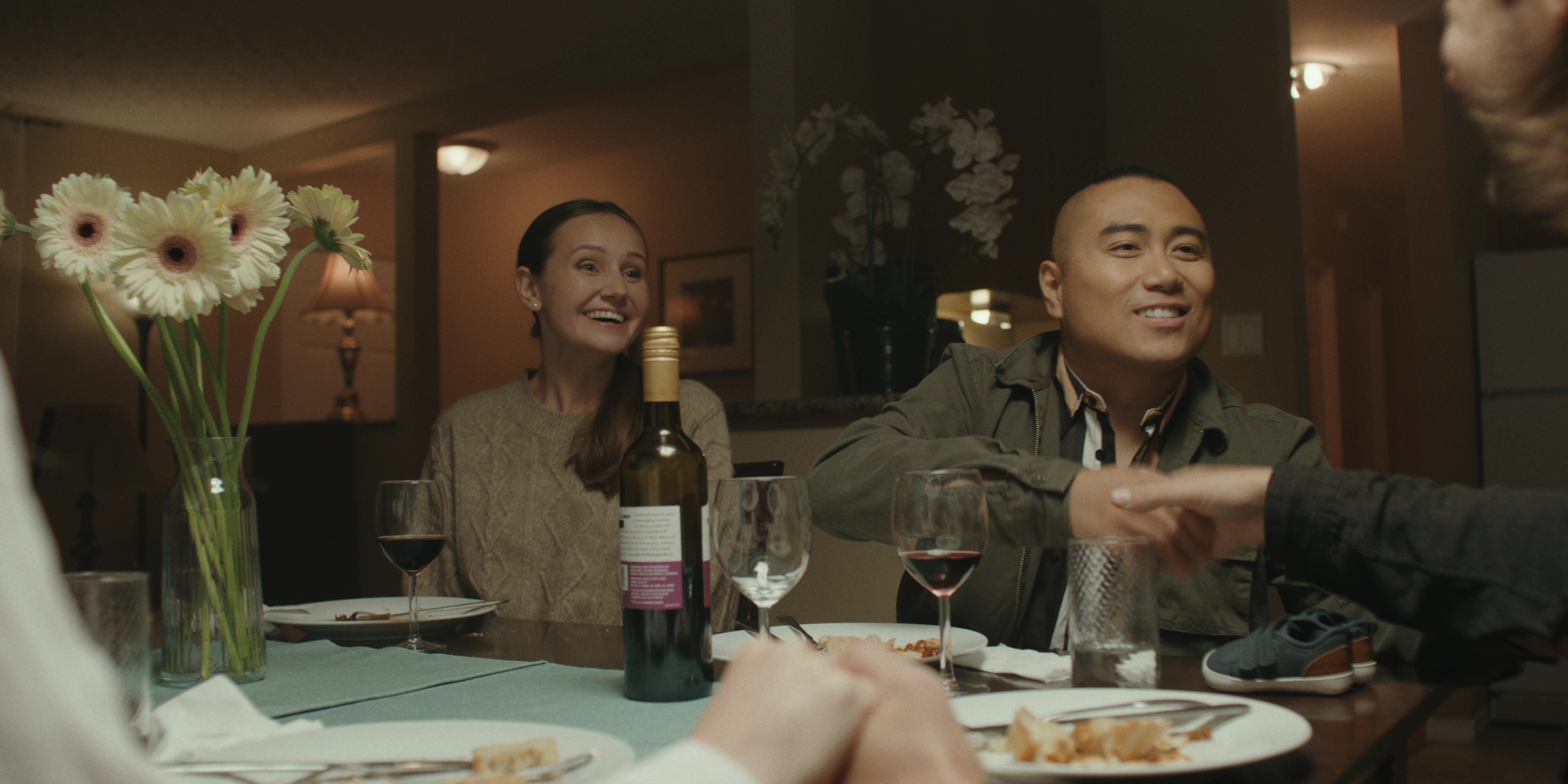 Two guests smile across a dinner table — Bottom of the bottle