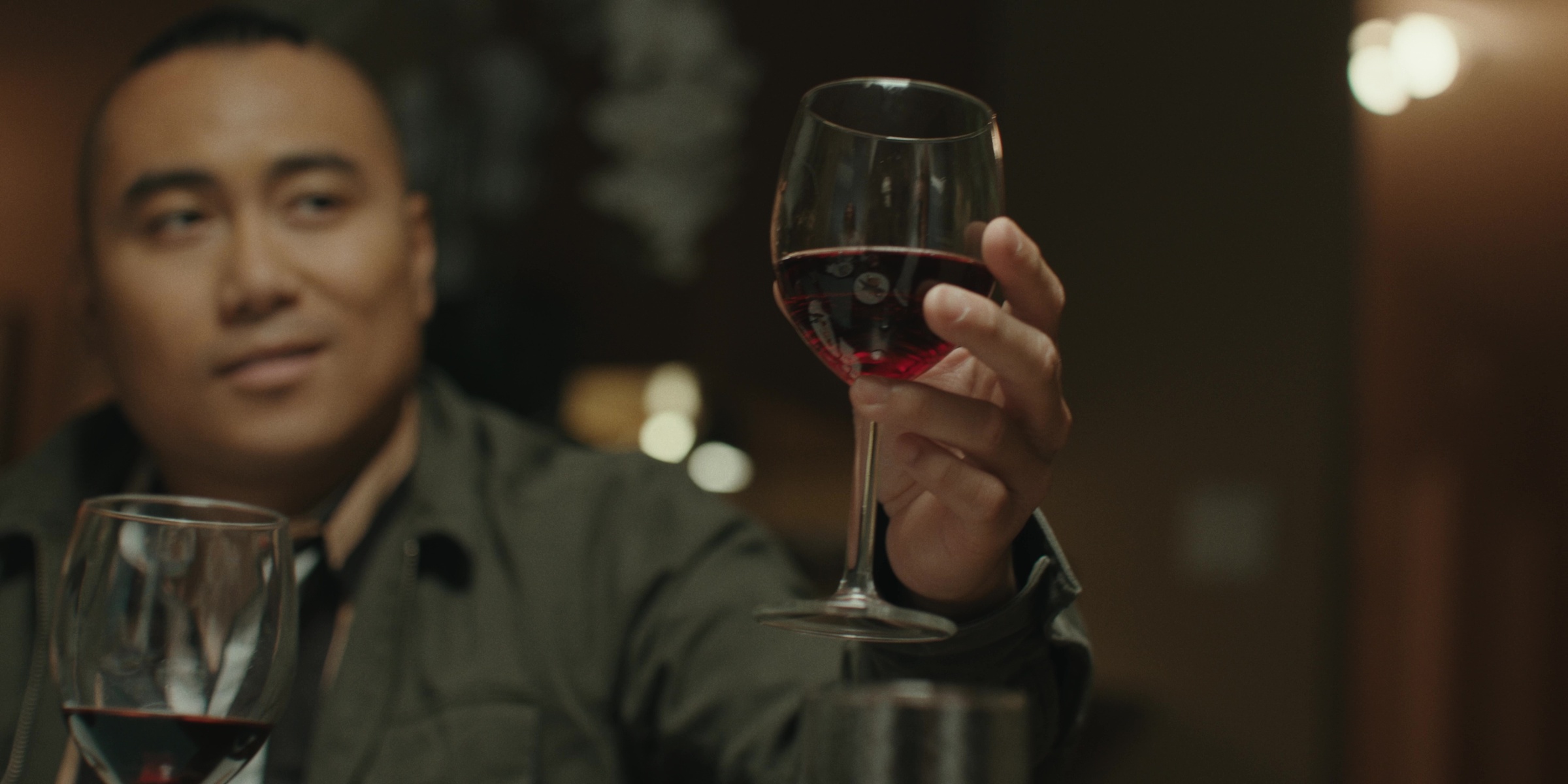 A dinner guest raises a glass of red wine — Bottom of the bottle