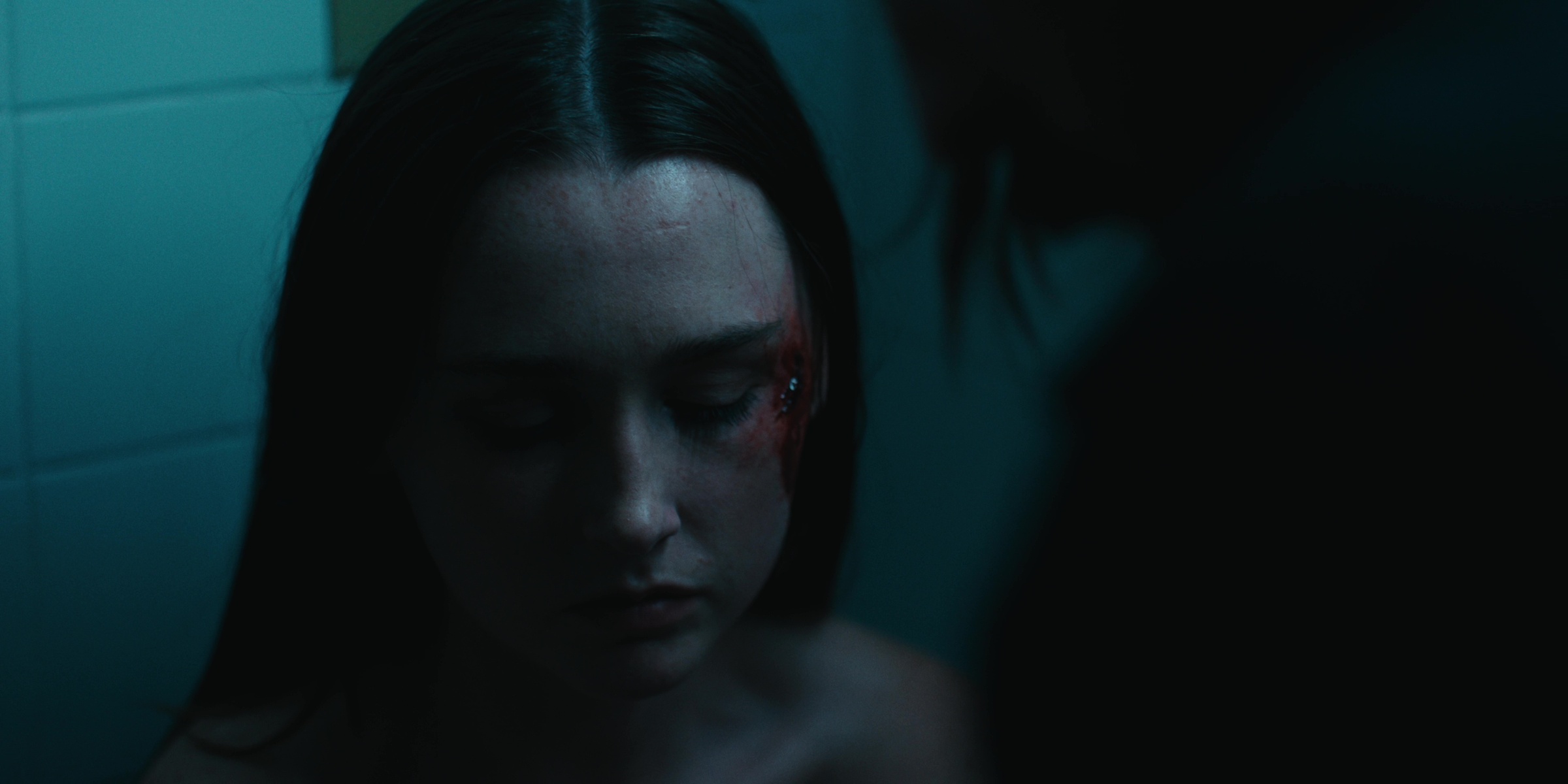 A woman looks down in a blue-lit bathroom — Bottom of the bottle