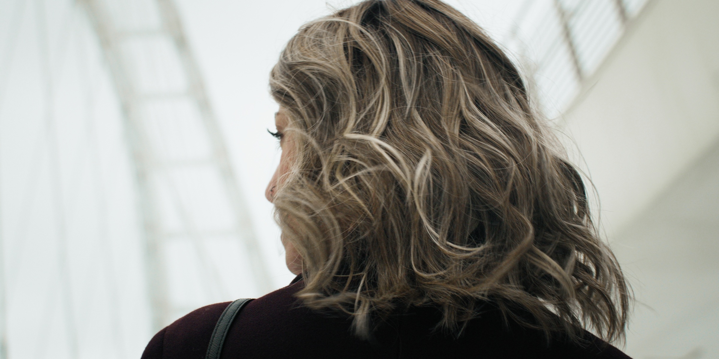 Close-up of a woman’s wavy blonde hair beside a bright window — Chiquel
