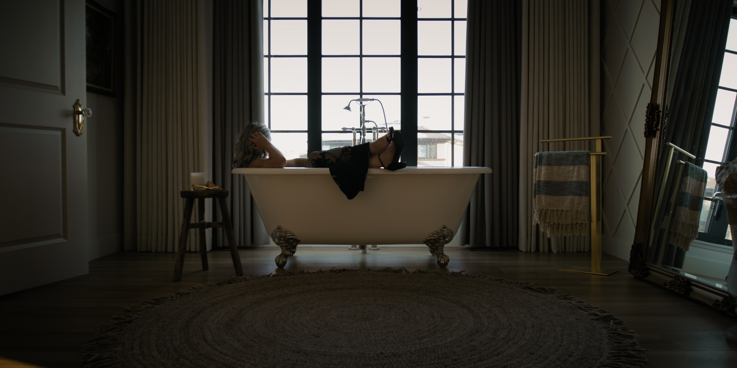 A woman reclines in a freestanding bath beneath a large window — Chiquel