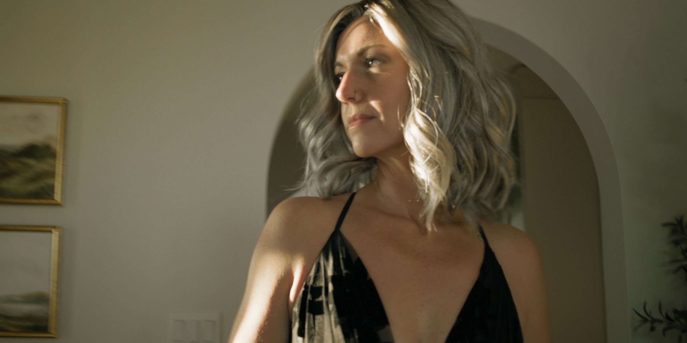 Warm sunlight catches a blonde woman in a black dress — Chiquel