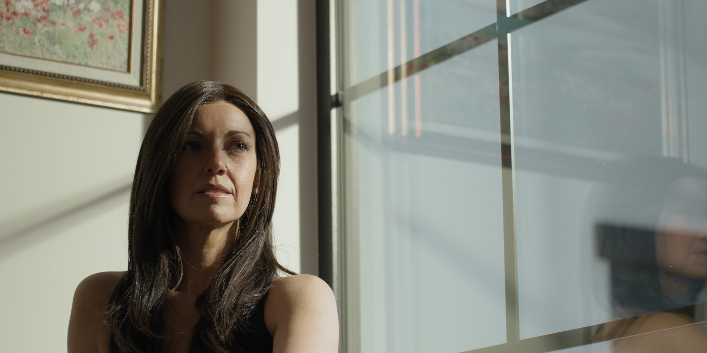 A brunette woman sits beside a sunlit window — Chiquel