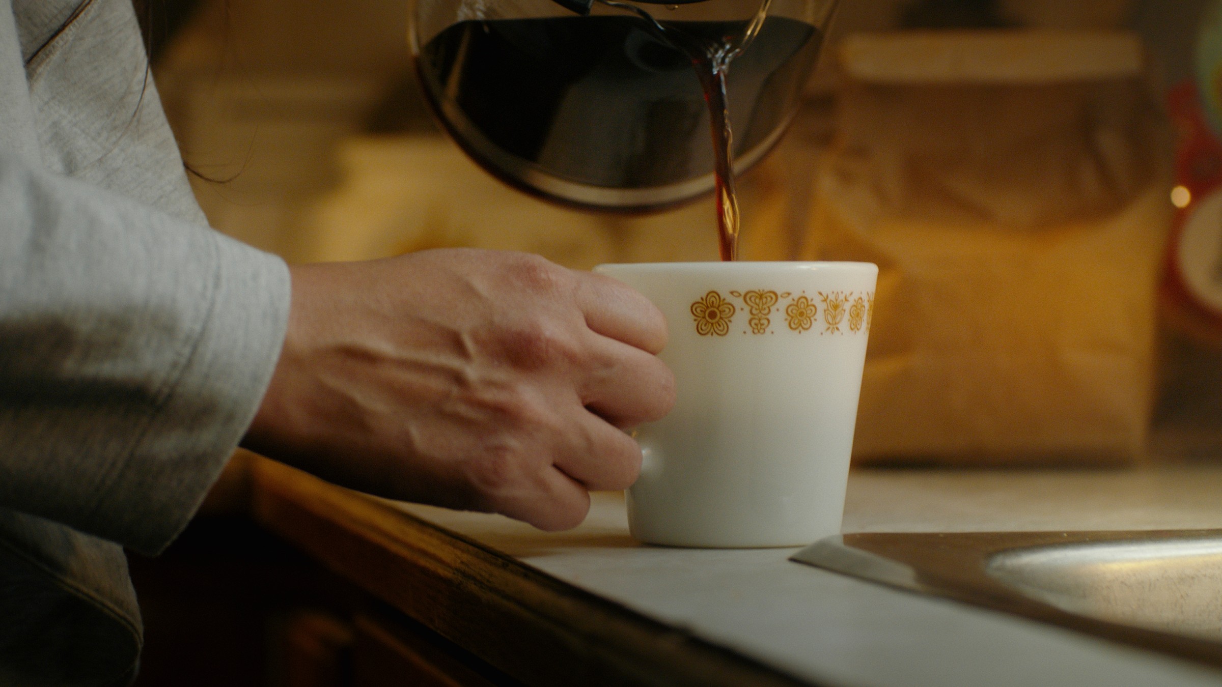 A hand rests beside a white mug on a kitchen counter — Communikit