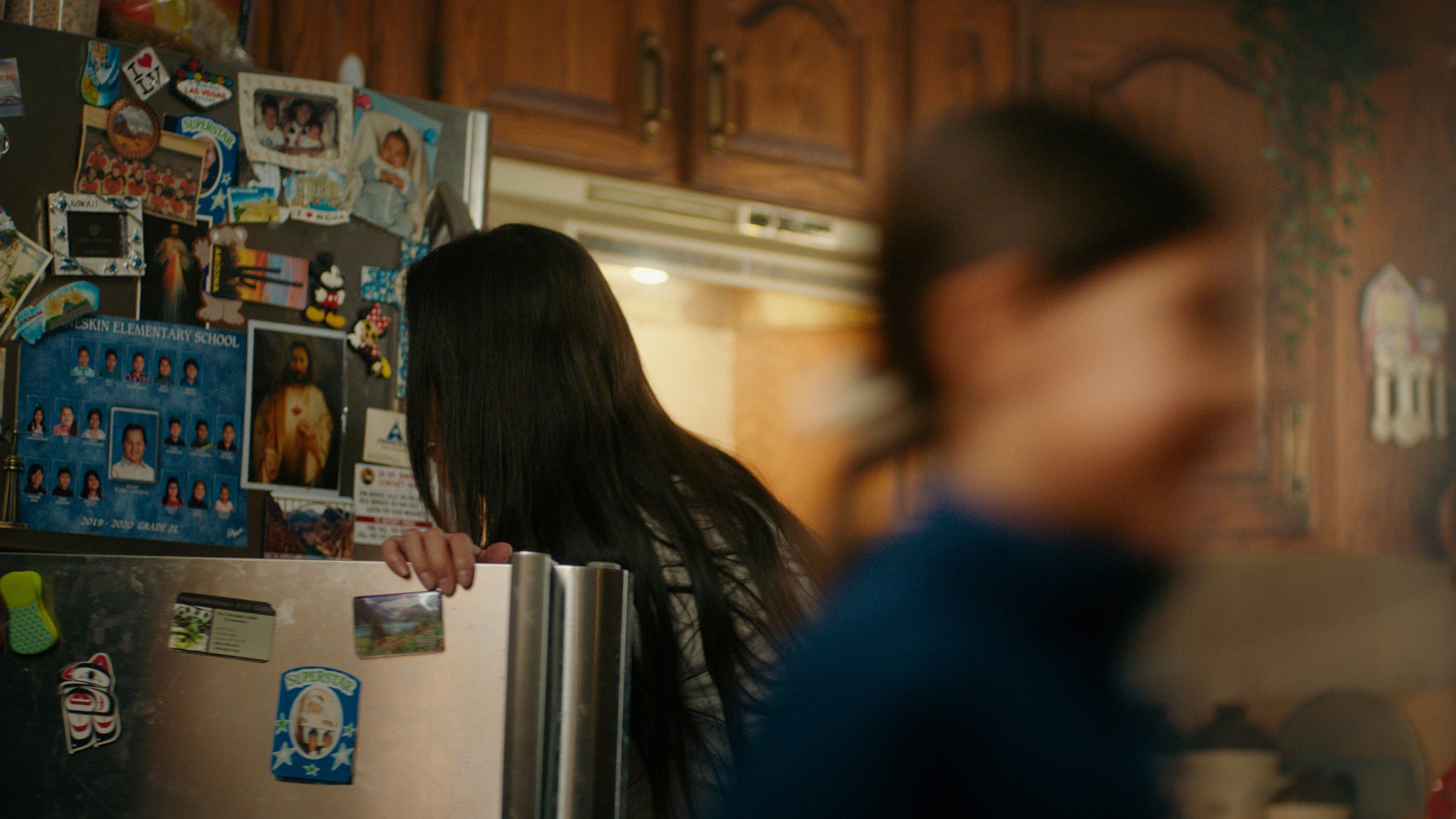 A woman stands by a refrigerator as a child passes through the kitchen — Communikit