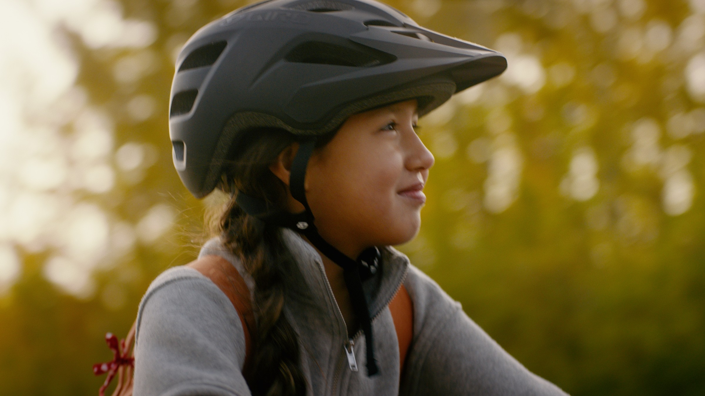 A helmeted child smiles in profile beside autumn trees — Communikit