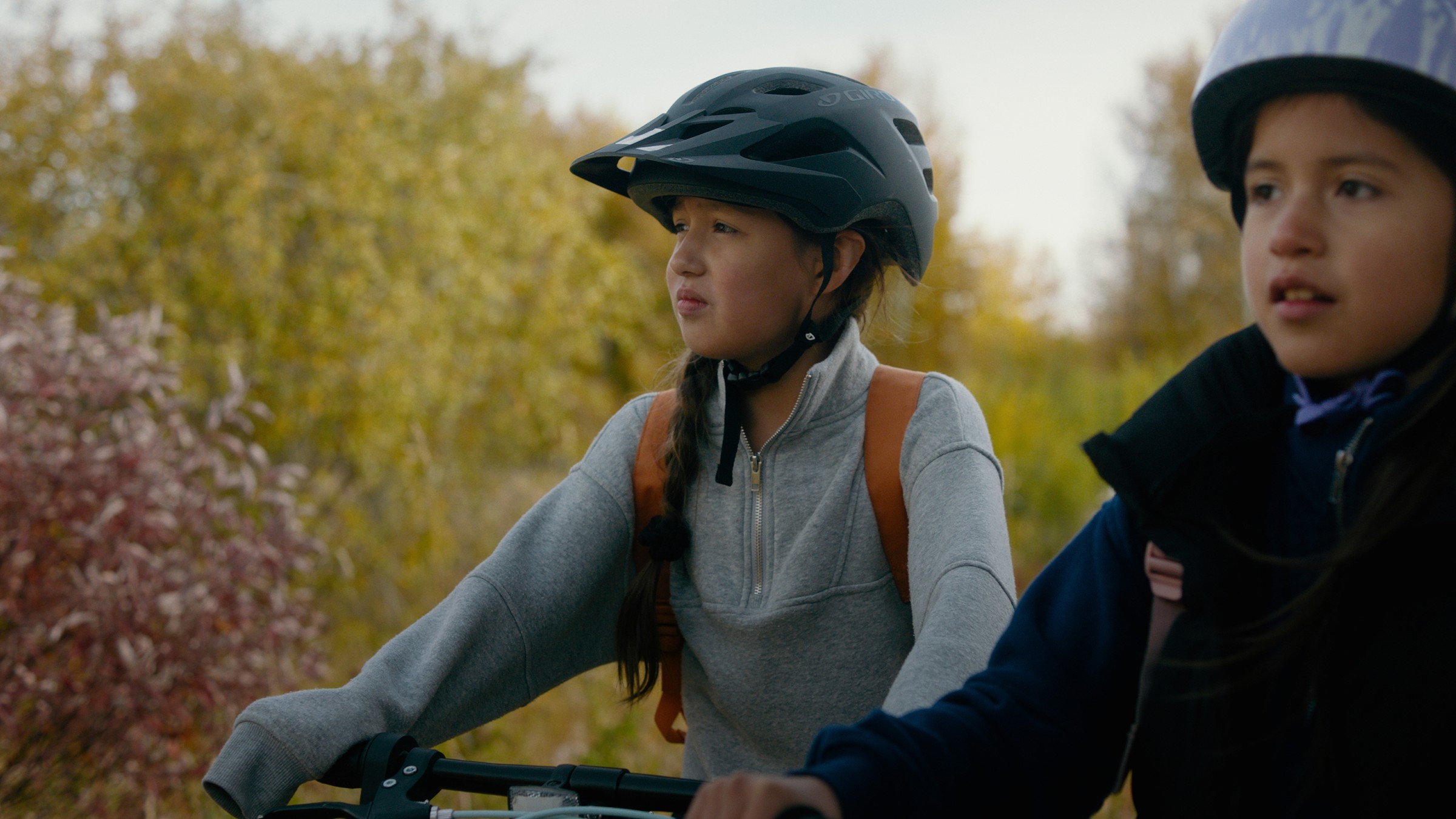 Two helmeted children look ahead from their bicycles — Communikit