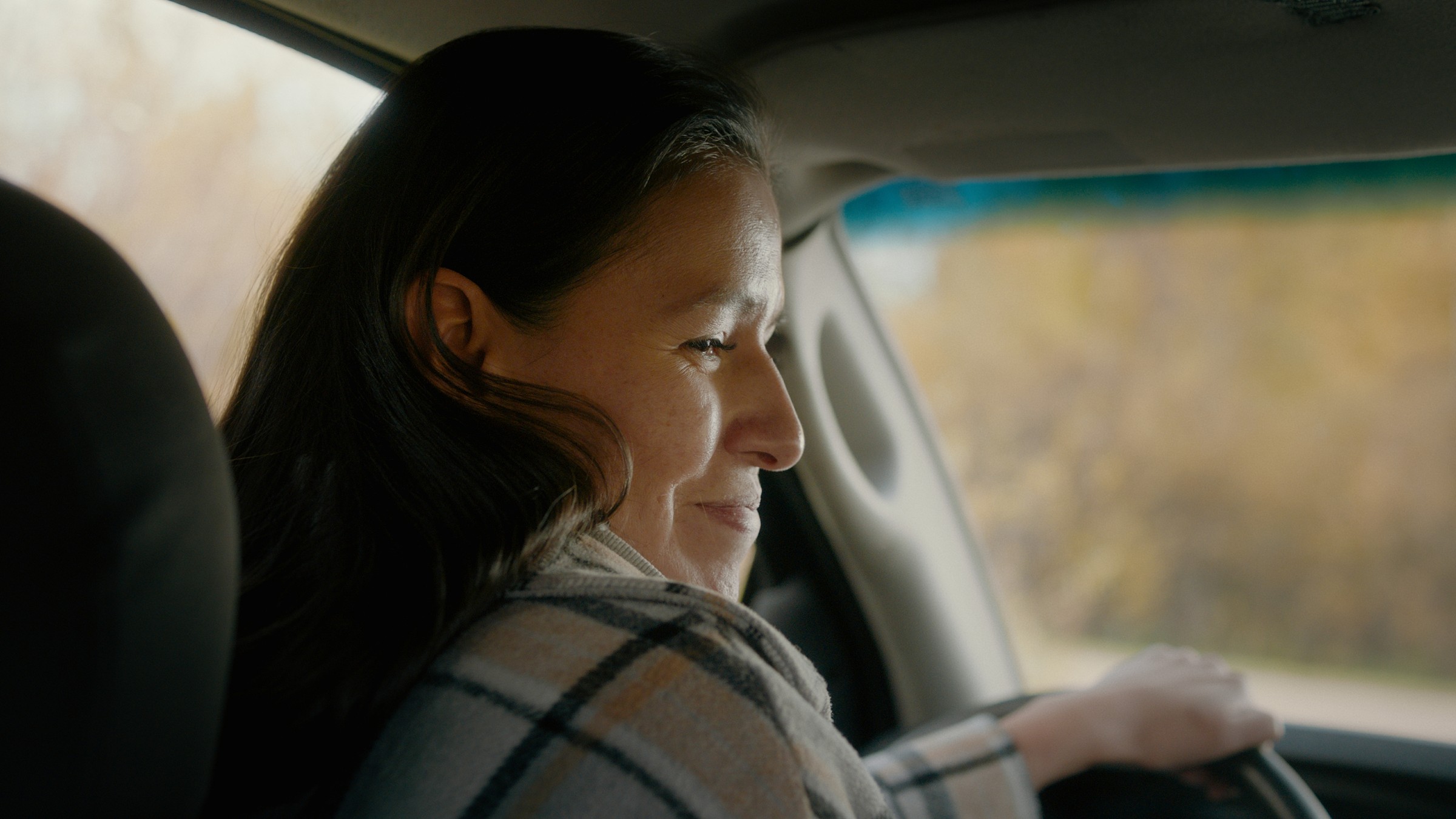 A woman looks back from the driver's seat — Communikit
