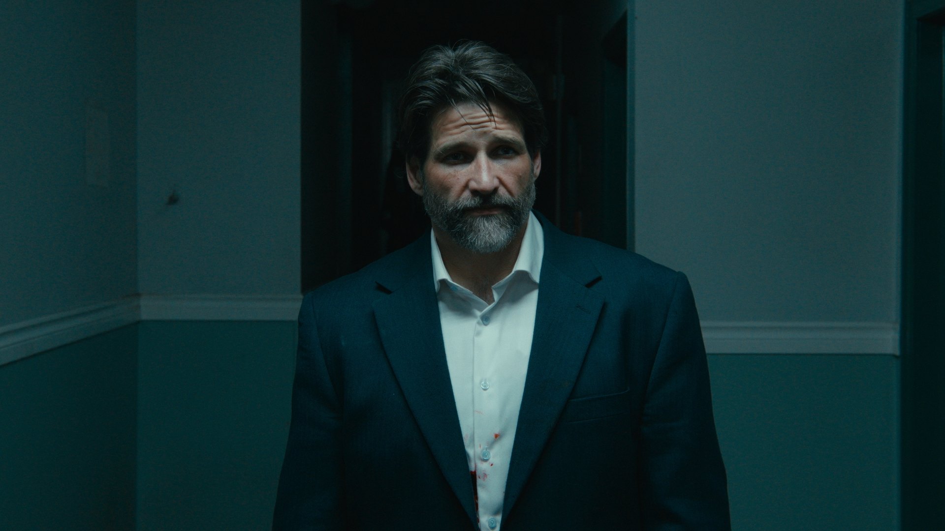 A man in a dark suit standing in a doorway — Crossroads