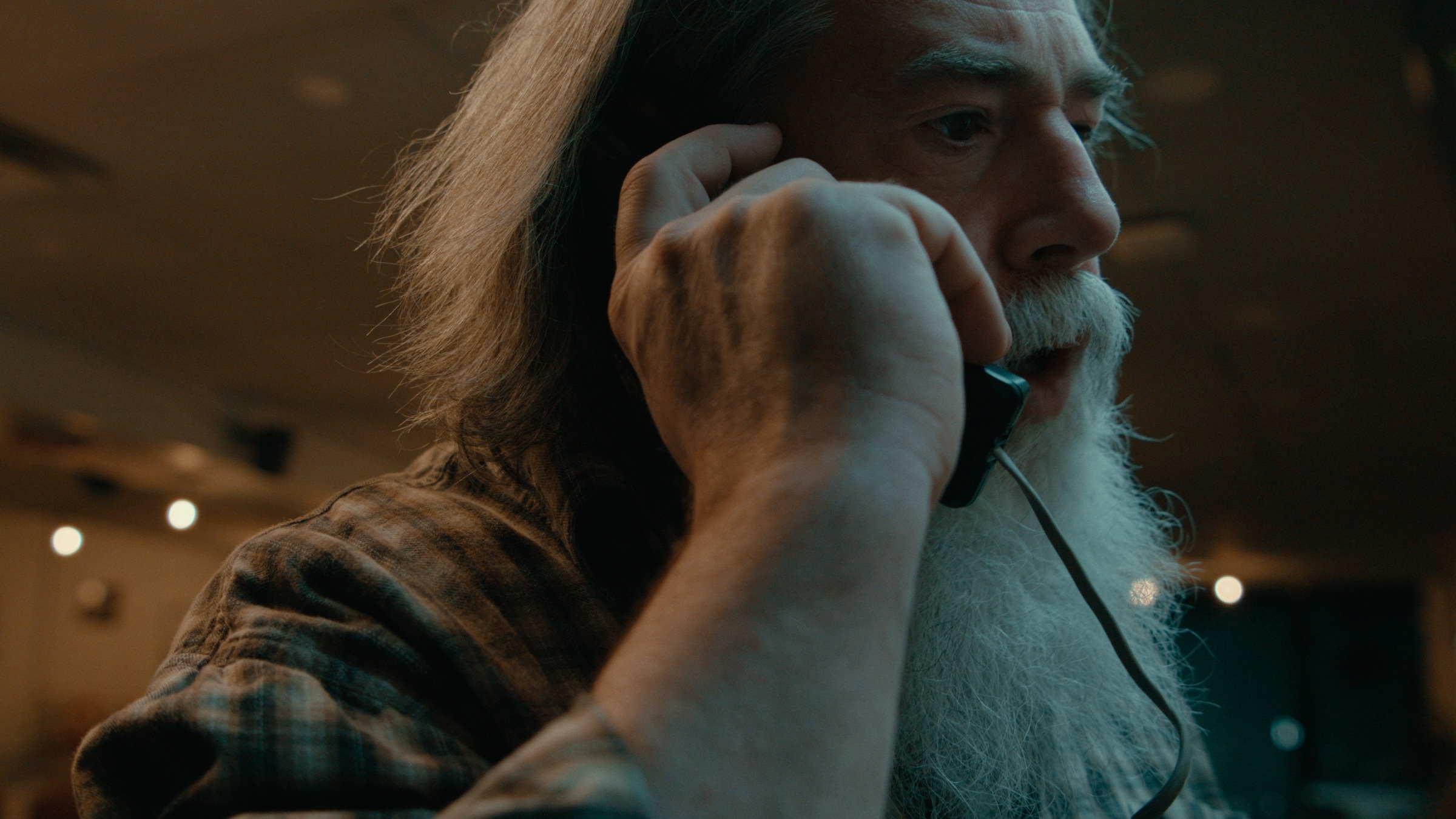 A long-bearded bartender holds a phone to his ear — Crossroads