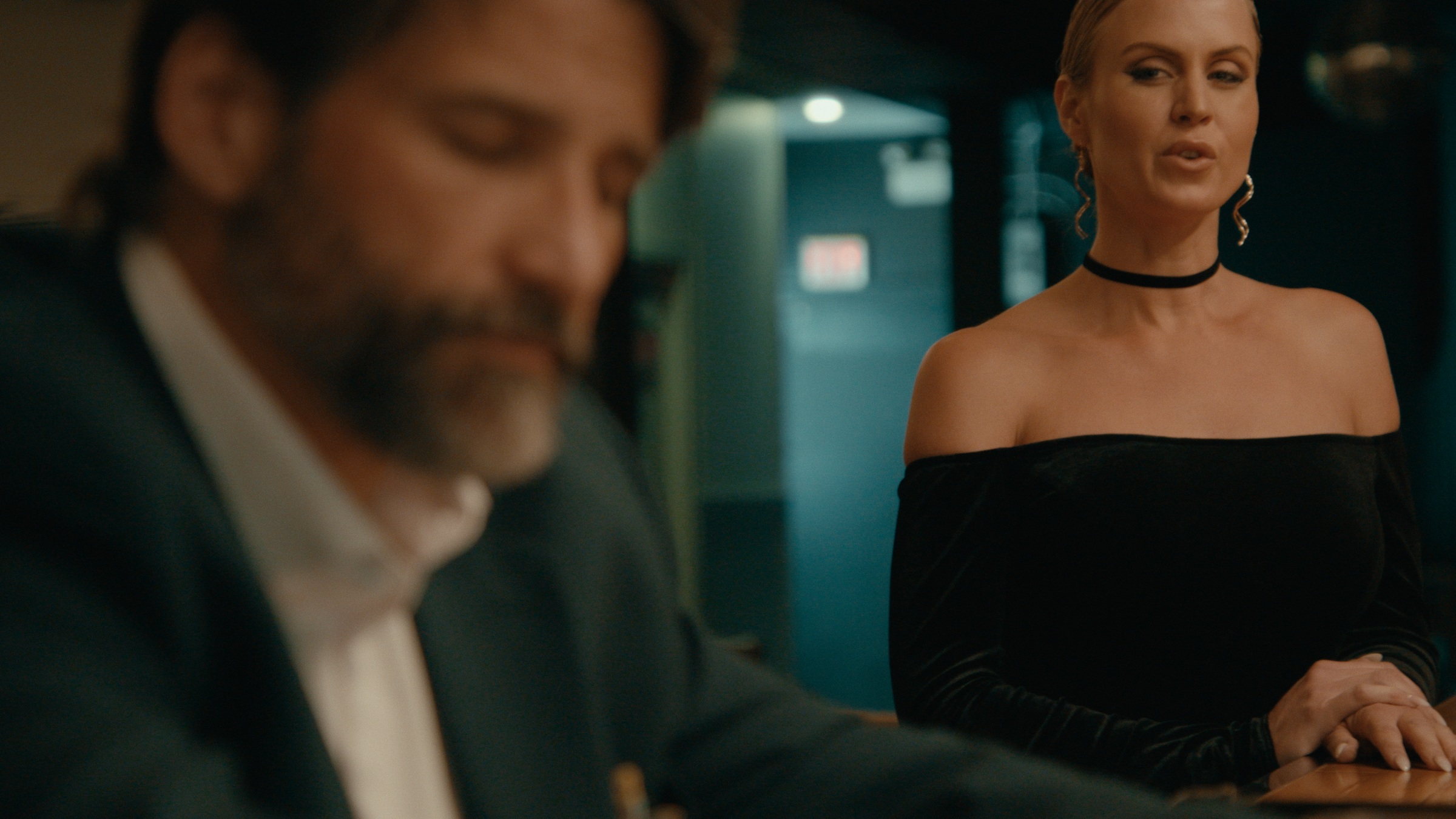 A woman in a black dress stands beside a seated man at a bar — Crossroads