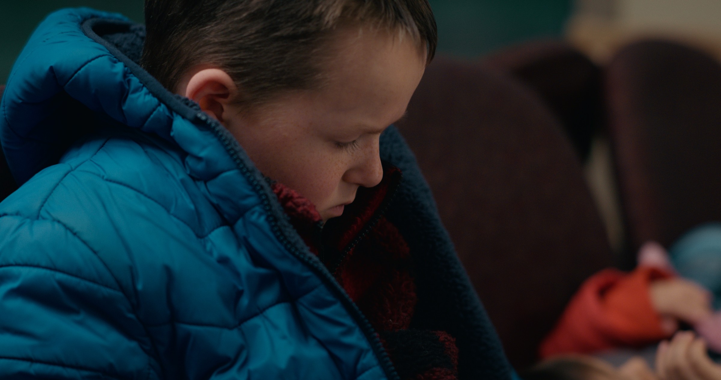 Close-up of a boy looking down in a blue winter coat — Emergency