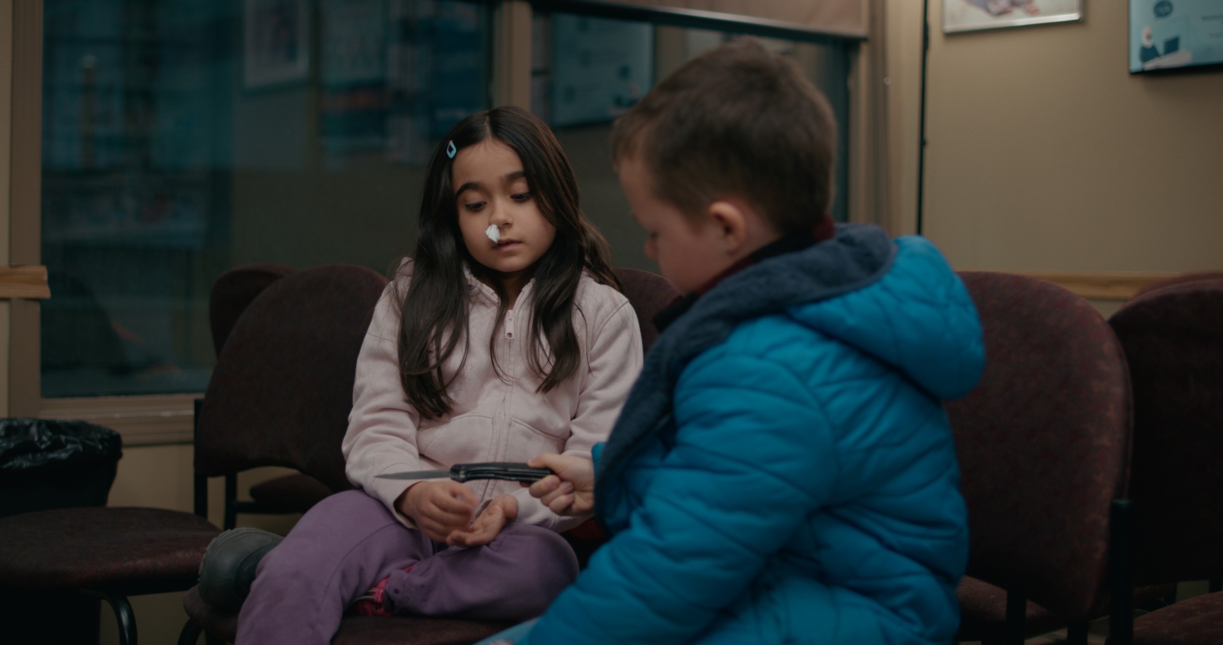 A girl and boy face each other in a waiting room — Emergency