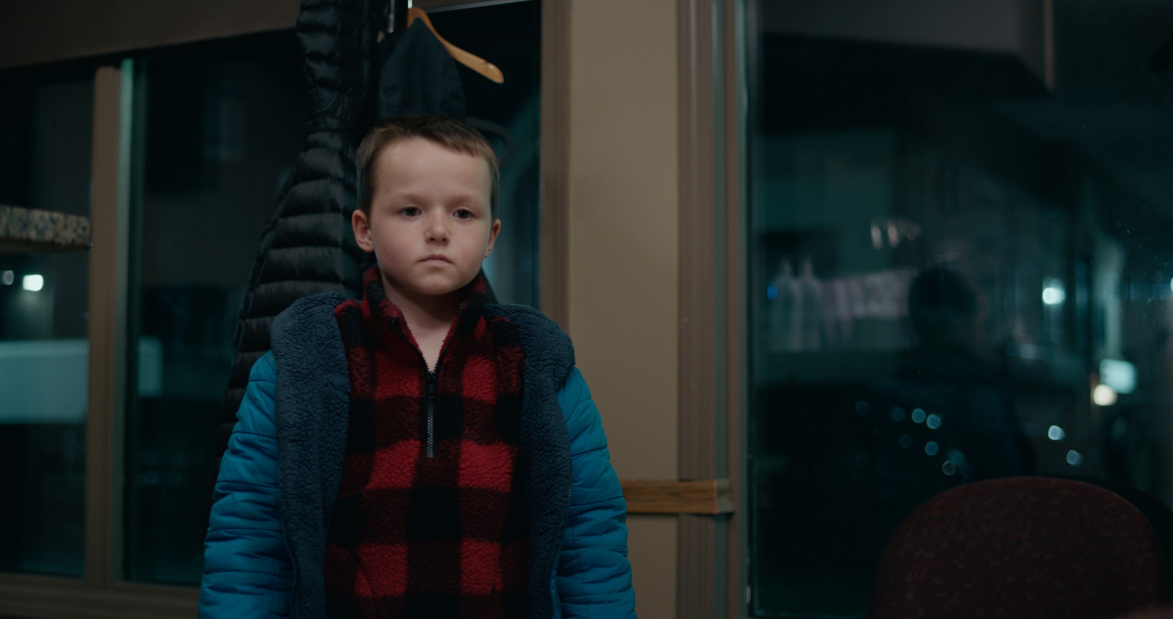 A boy stands beside waiting-room chairs at night — Emergency