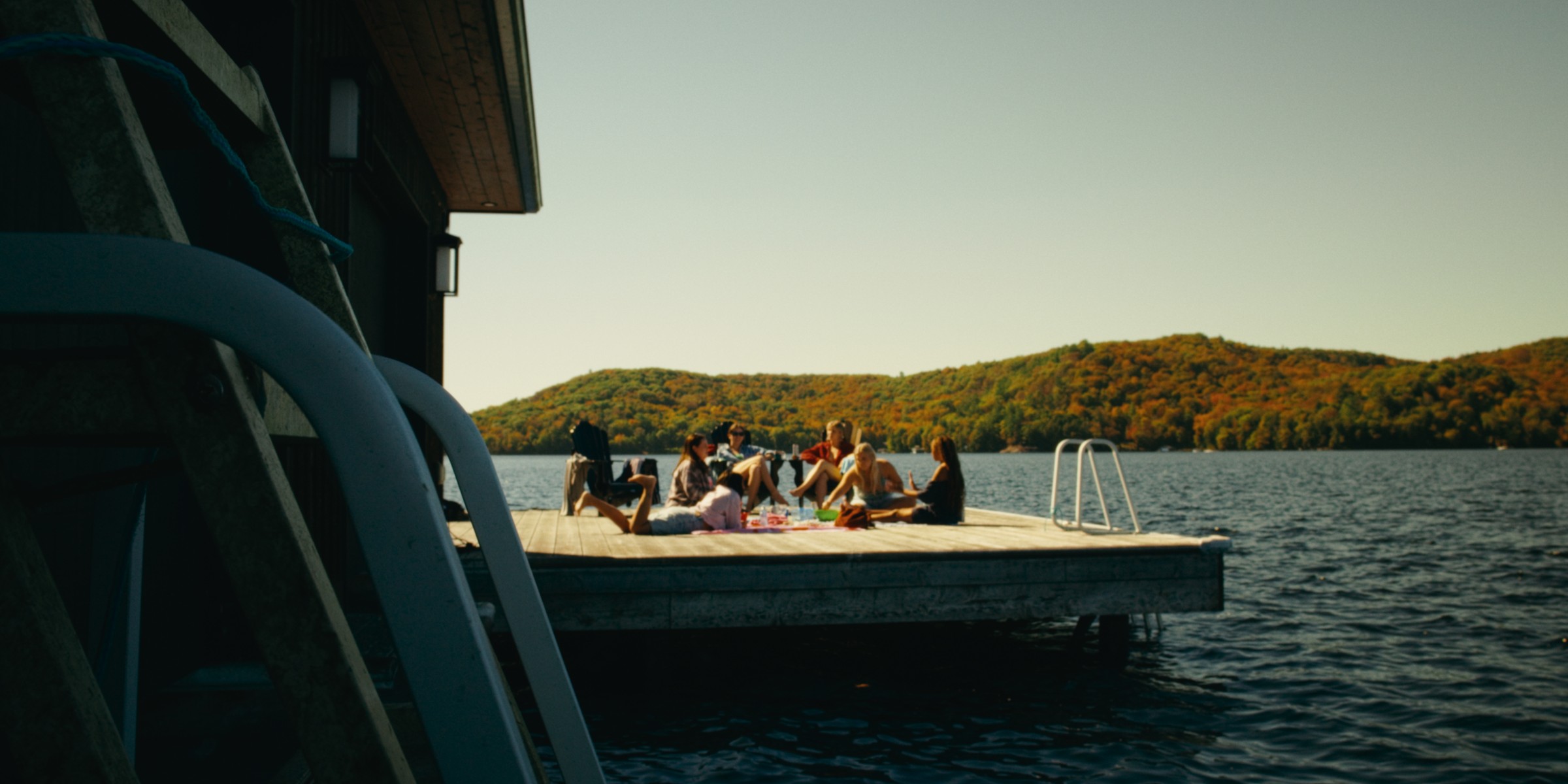 Friends gather on a sunlit dock beside a lake — Girls Weekend