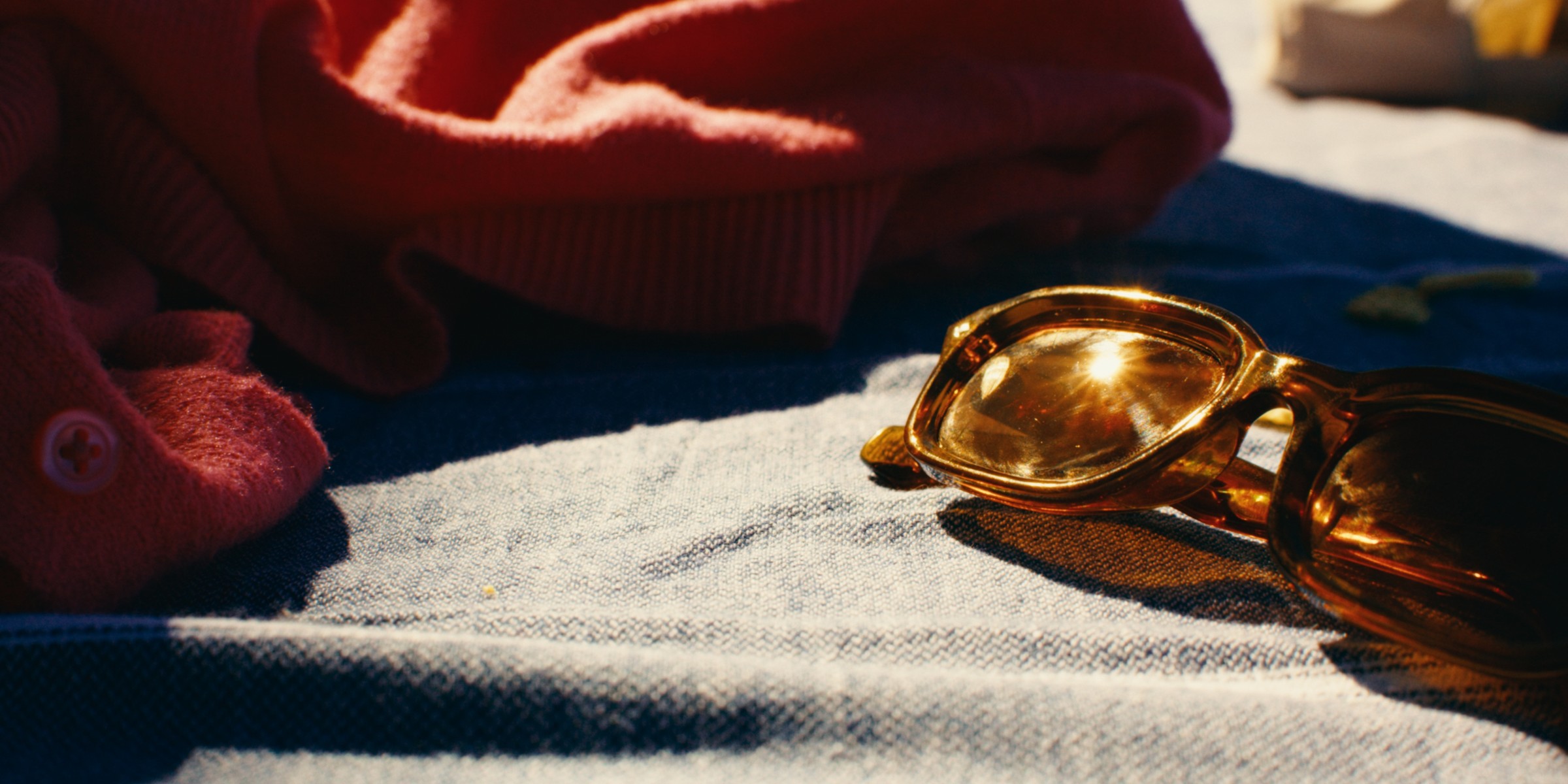 Hands beside amber sunglasses on a sunlit towel — Girls Weekend