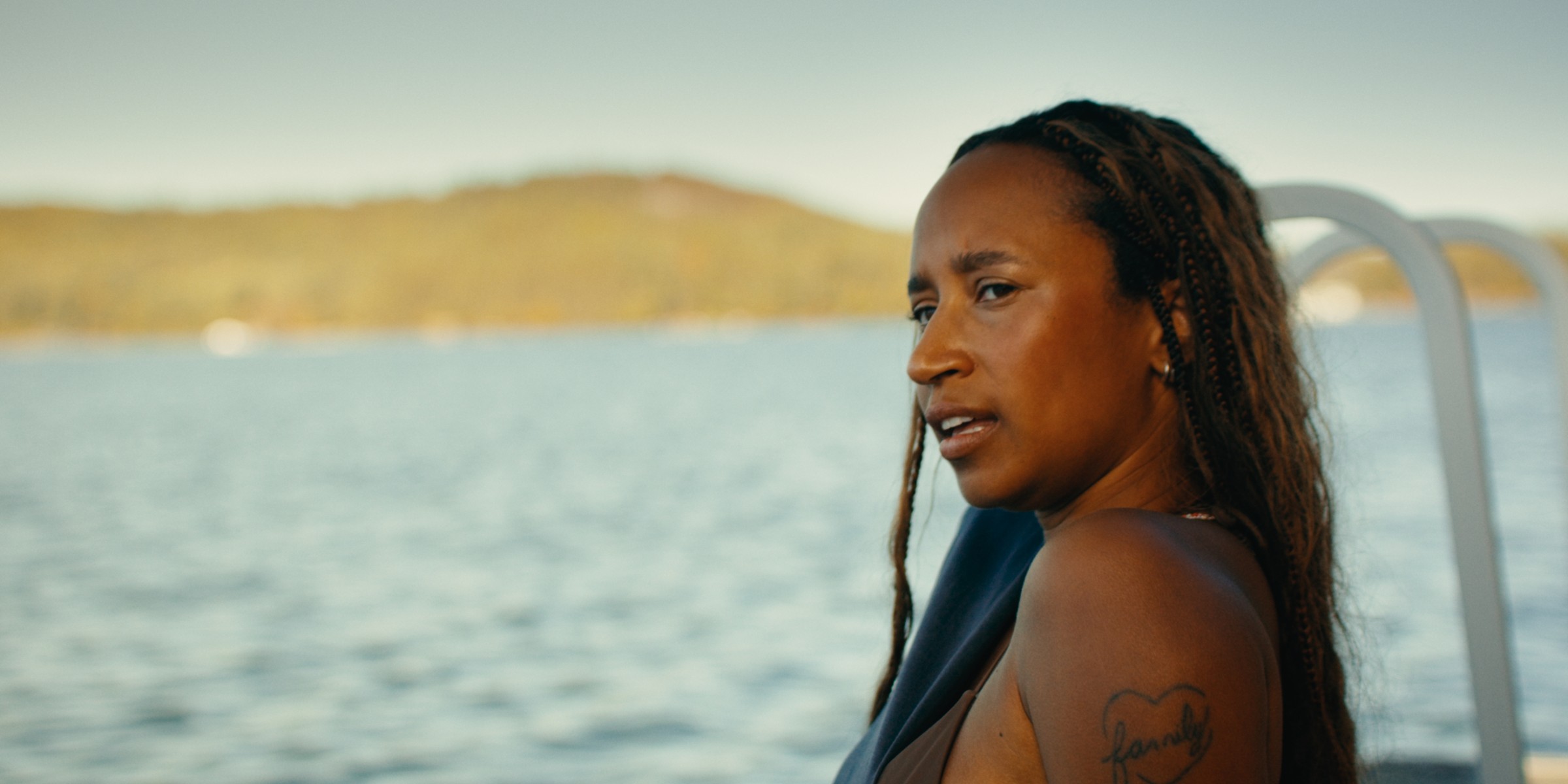 A woman with long braids looks back beside the lake — Girls Weekend