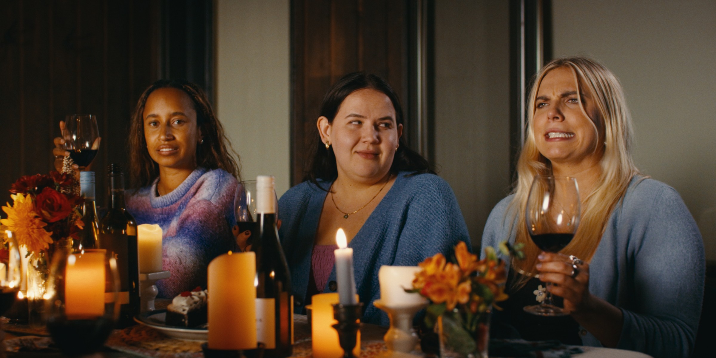 Three women sit together at a candlelit dinner table — Girls Weekend