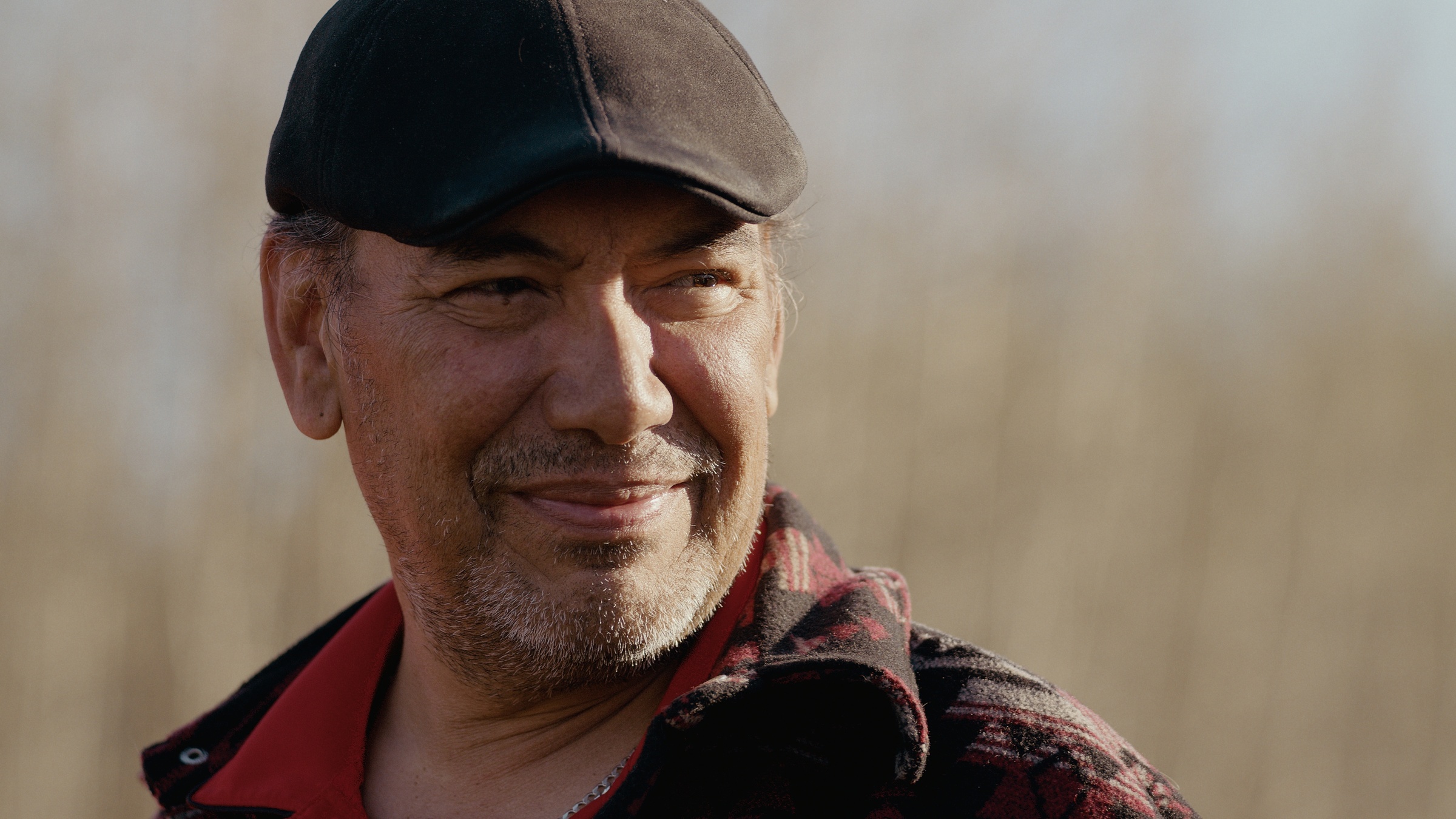 A man in a dark flat cap smiles outdoors — Home Fire