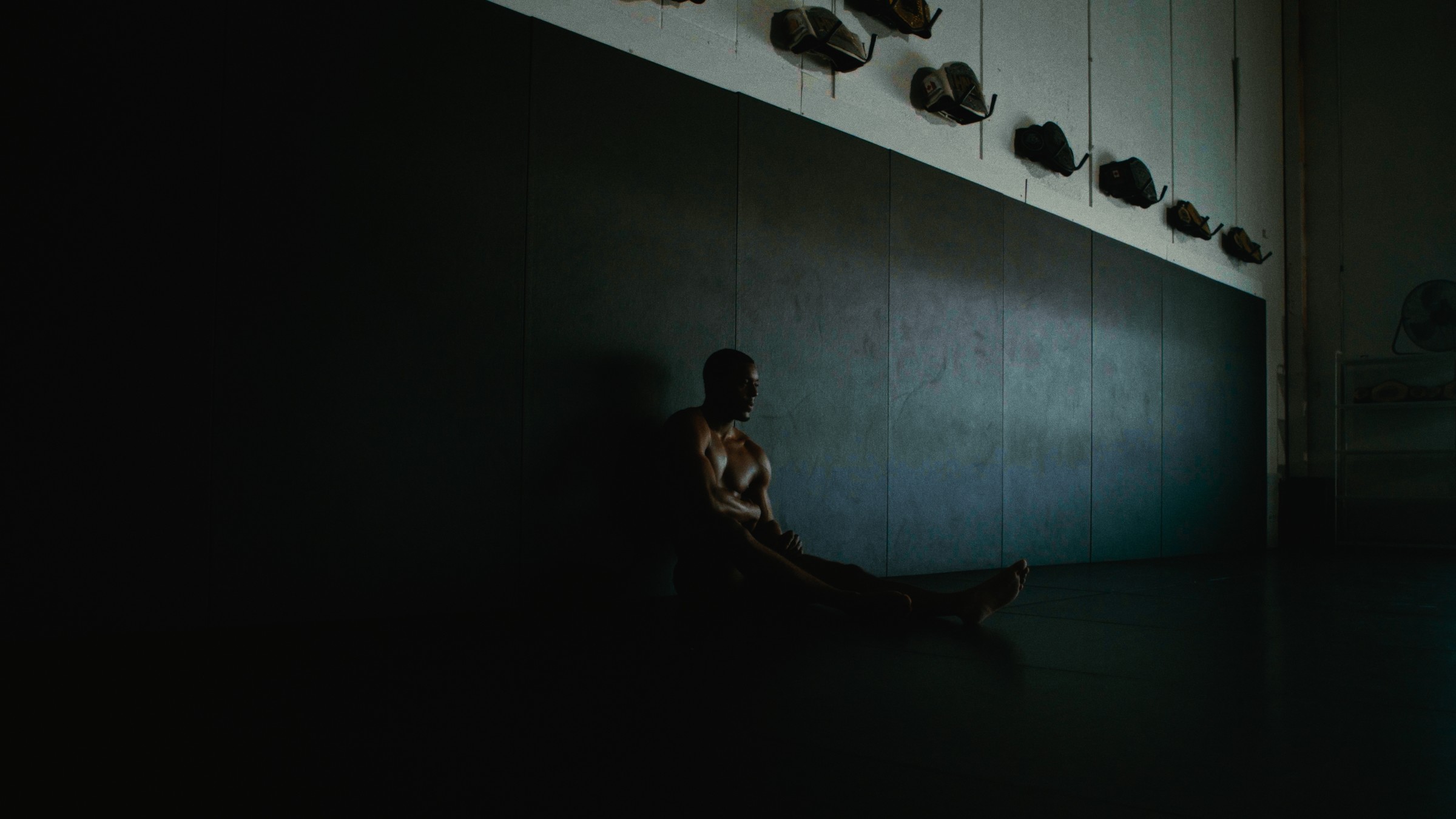 A boxer stands beside a training cage in a dark gym — Kinetic