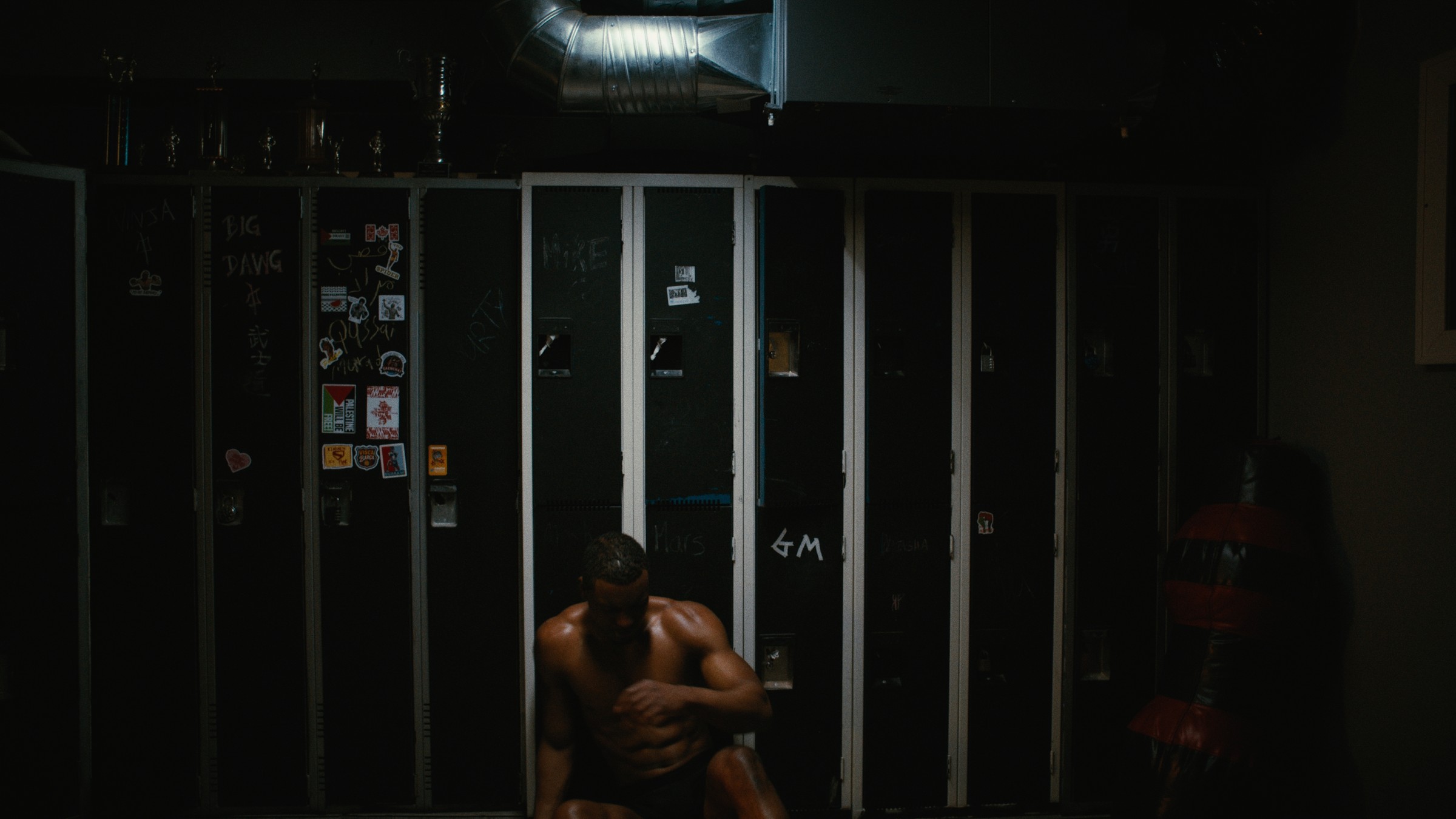 A boxer sits near a cage in a dark training room — Kinetic