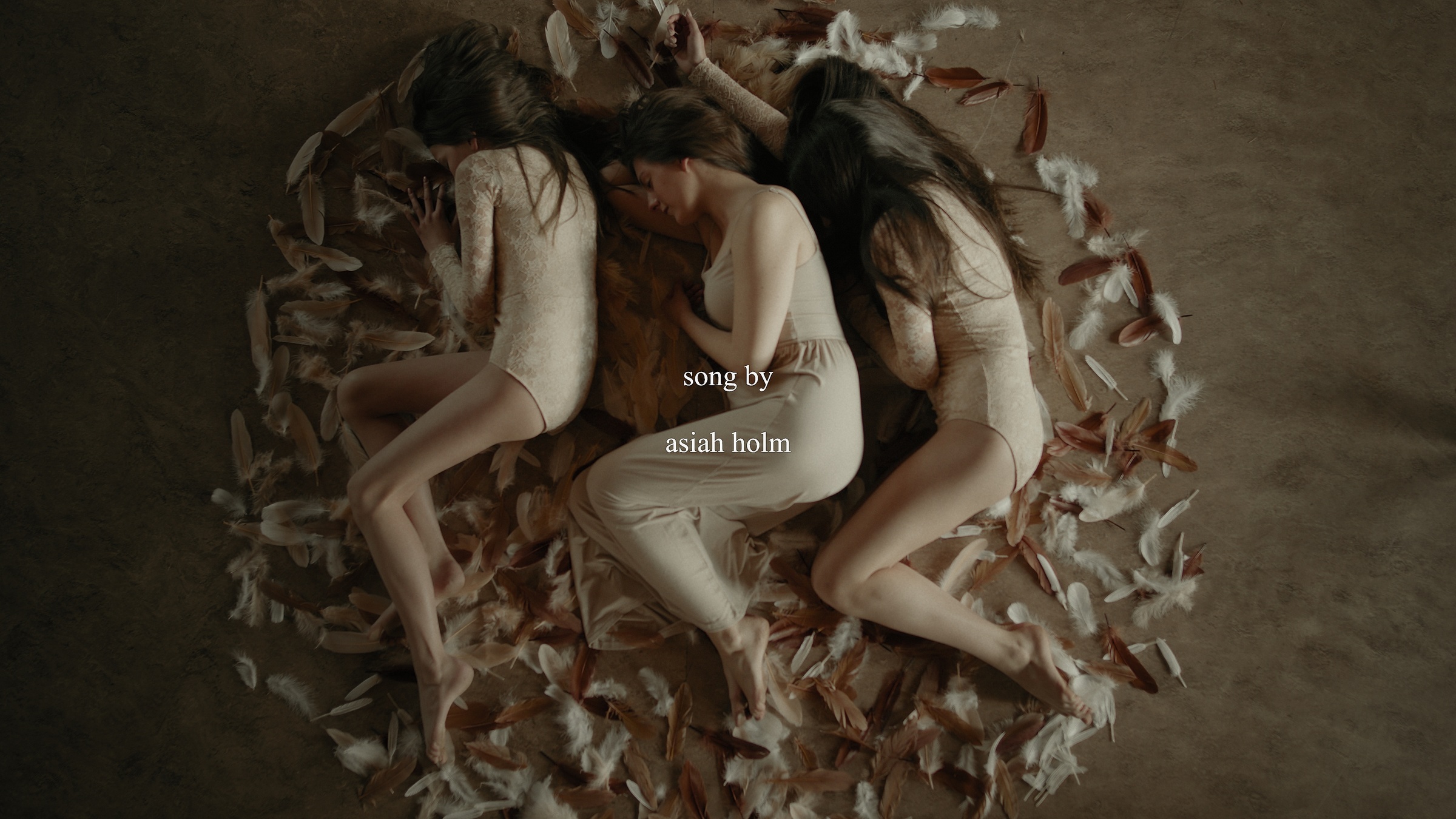 Three women lie together among feathers beneath the words song by asiah holm — Let Go