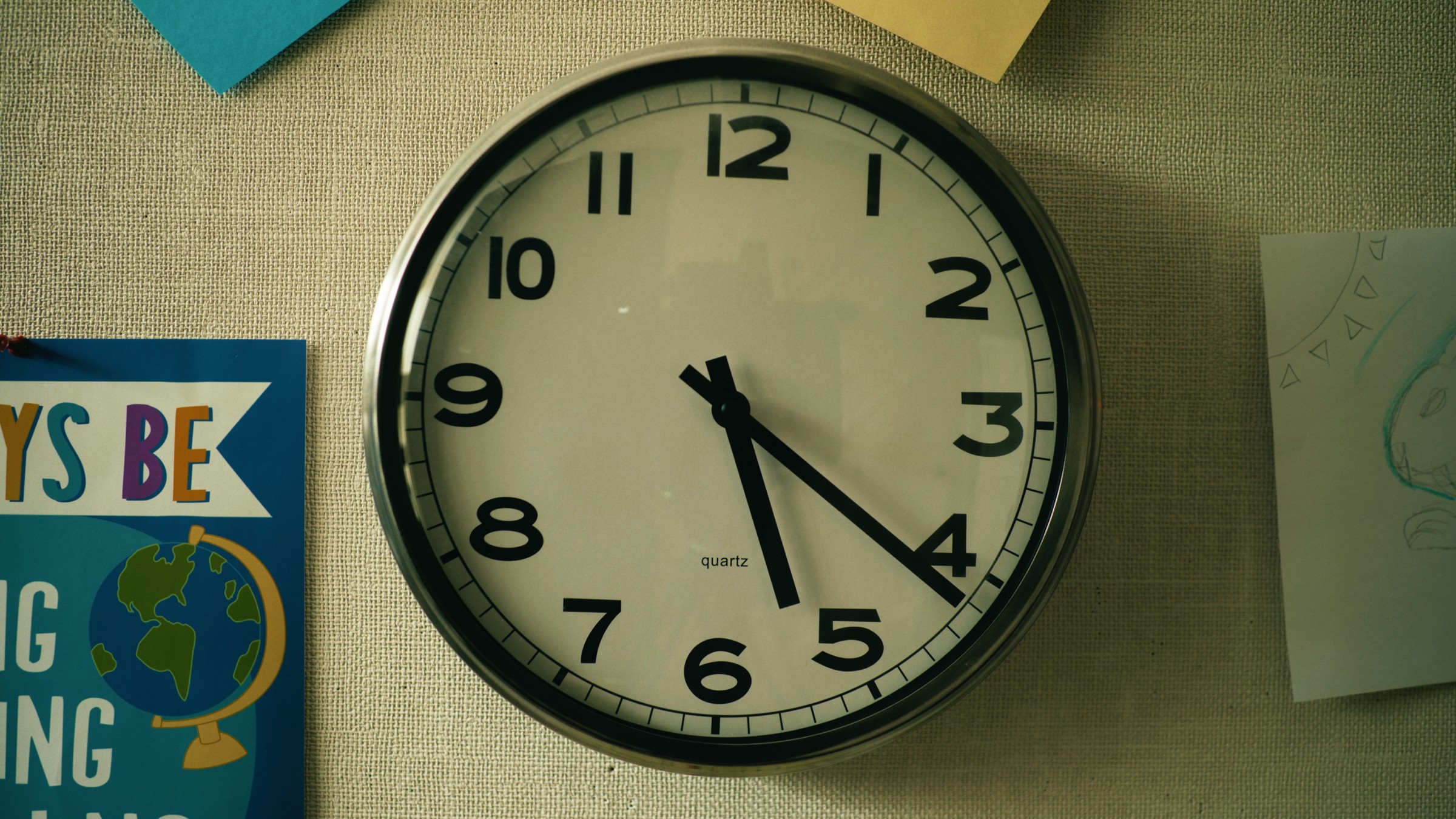 A round wall clock in a school hallway — Little Fangs