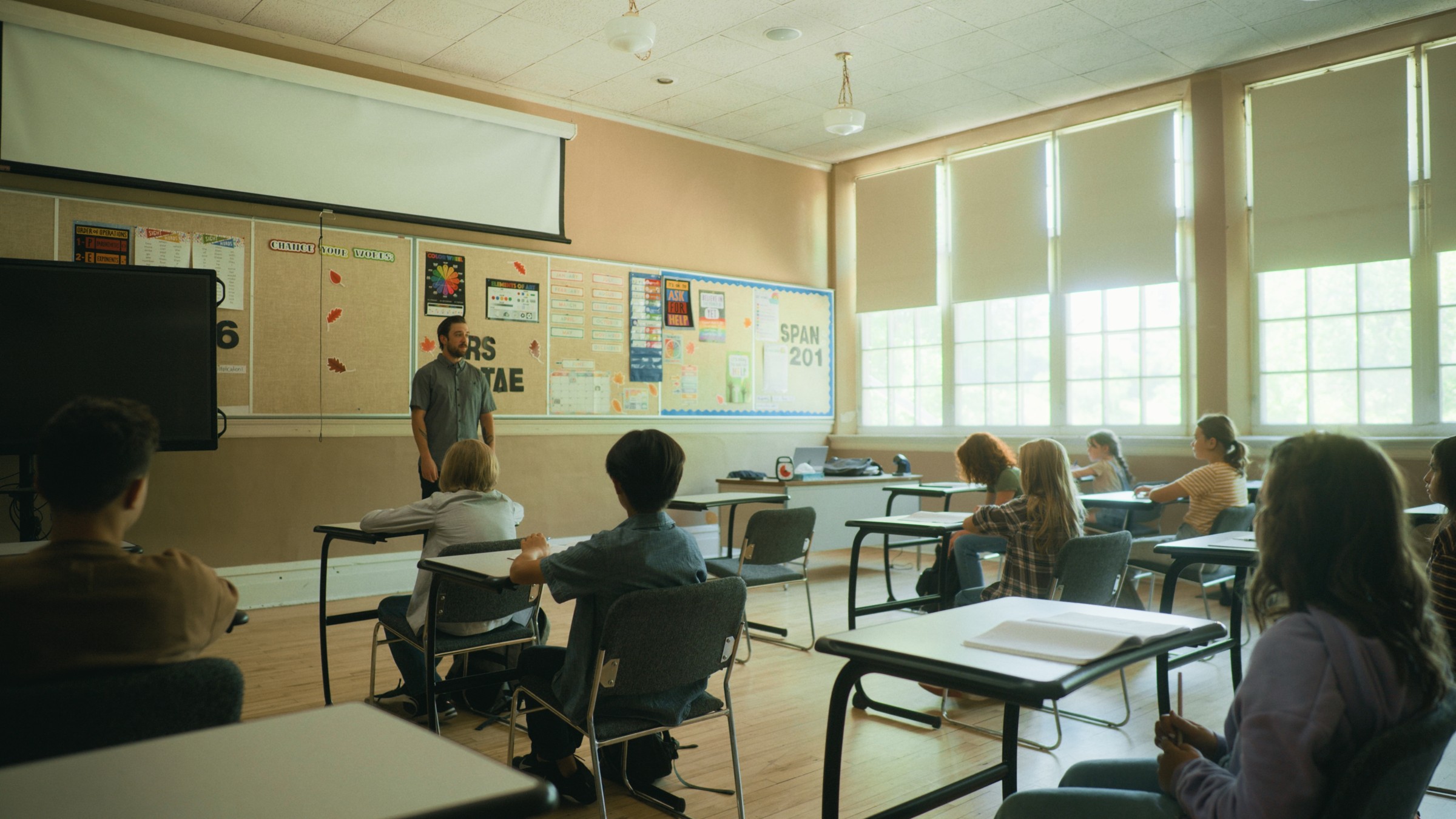Children sit at desks in a sunlit classroom — Little Fangs