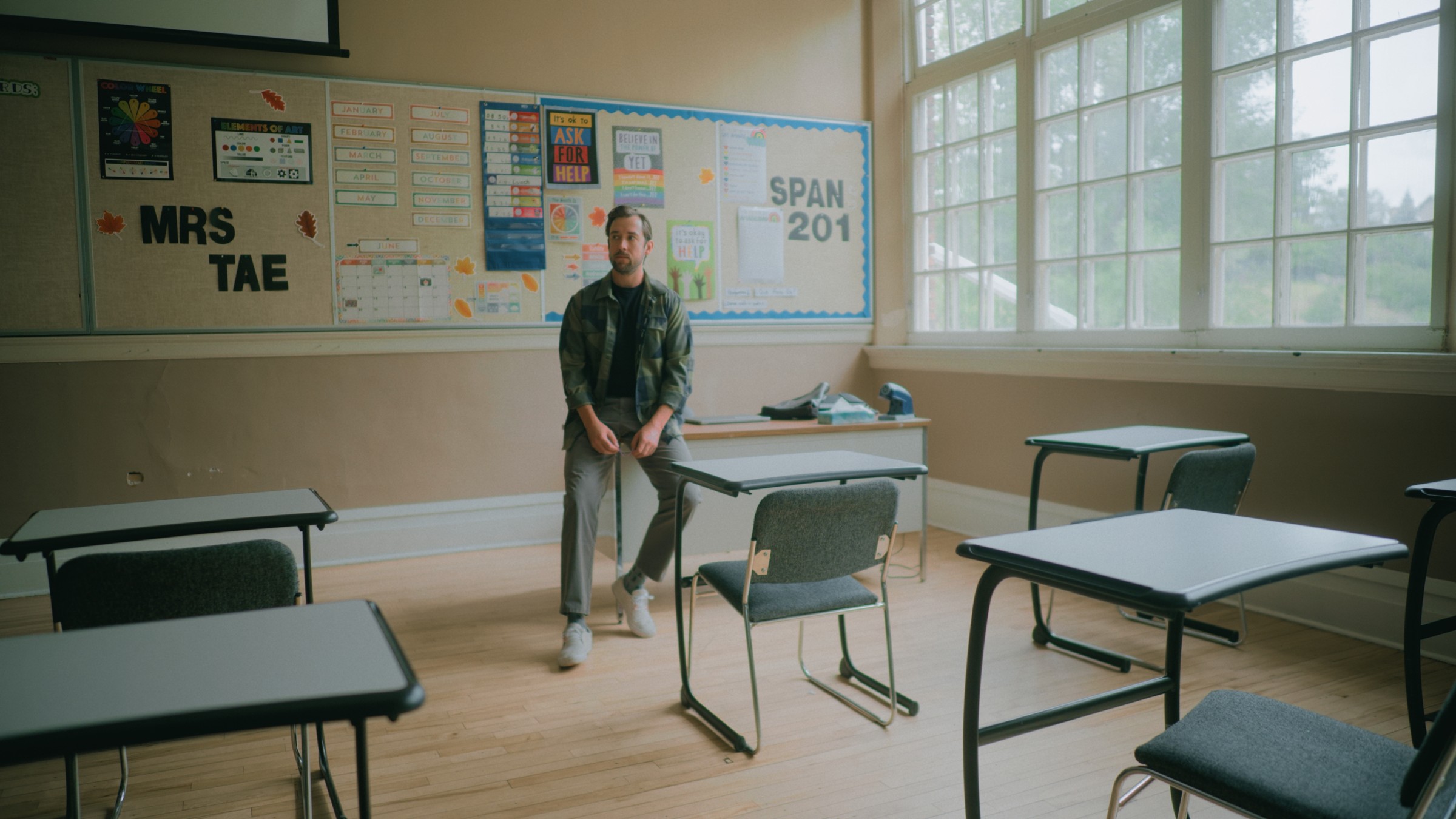 A man stands among empty school desks — Little Fangs