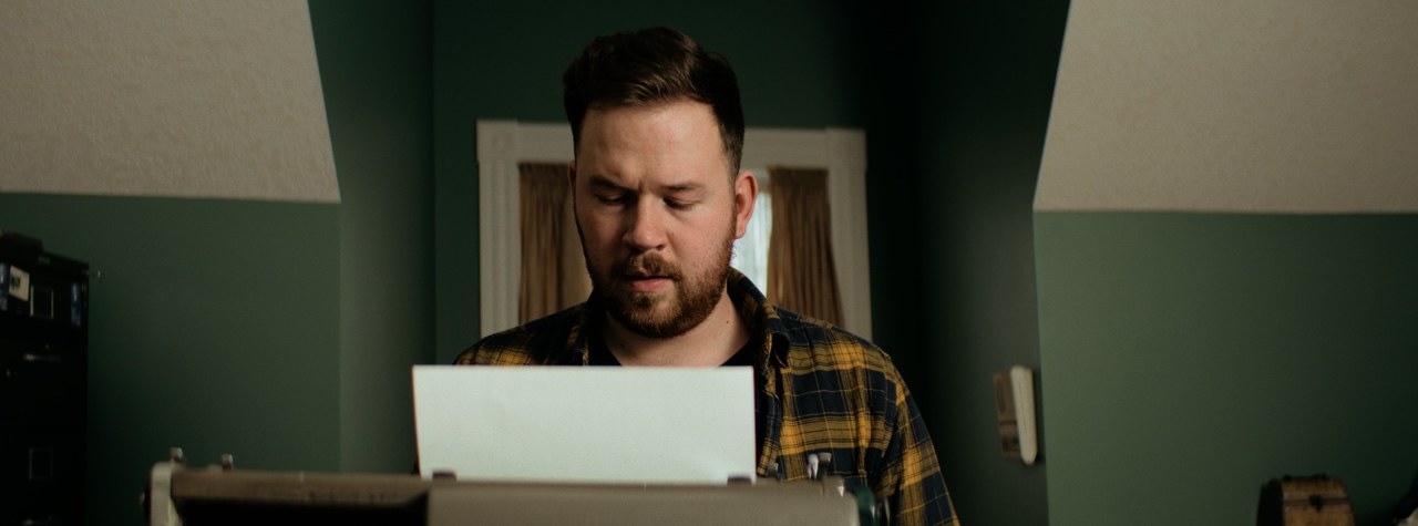 A man reading a letter in a green-walled room — Markings of Murder