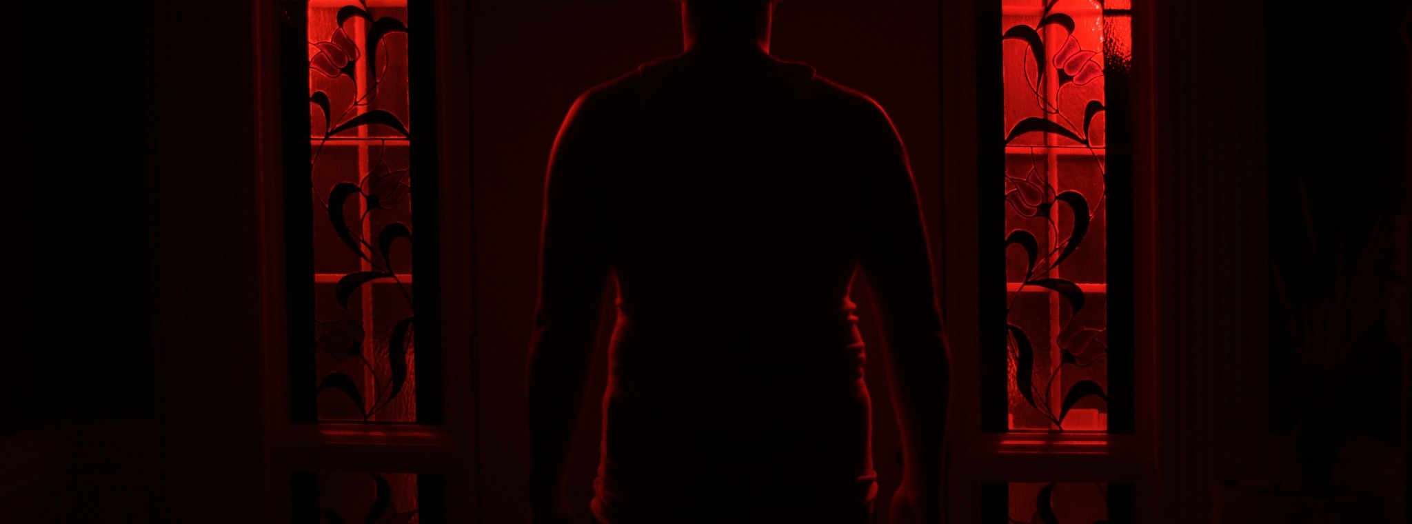 A silhouetted figure stands in a red-lit doorway — Markings of Murder