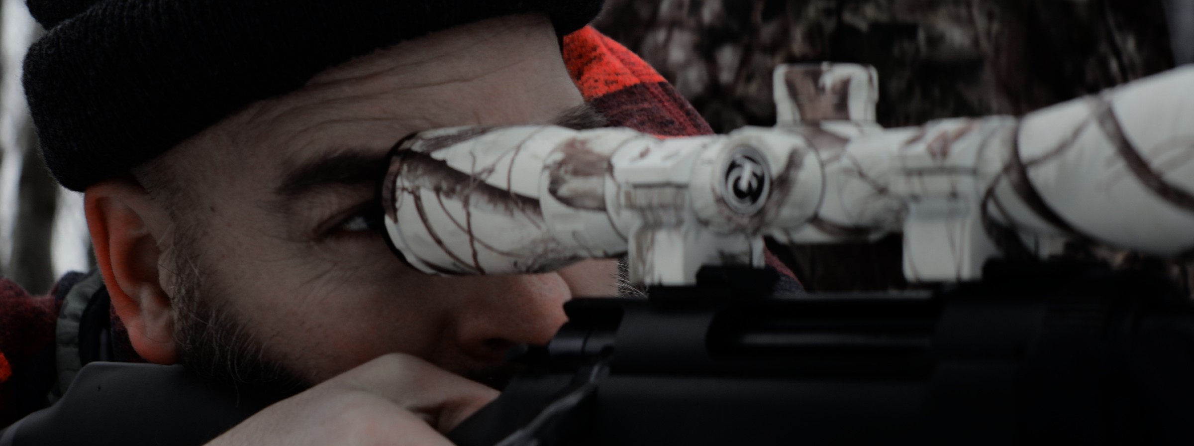 Close-up of a man looking through a rifle scope — Markings of Murder