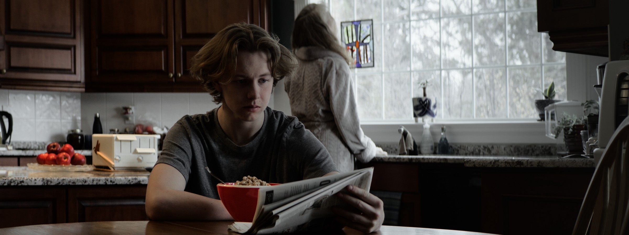 A man reads papers at a kitchen table — Markings of Murder