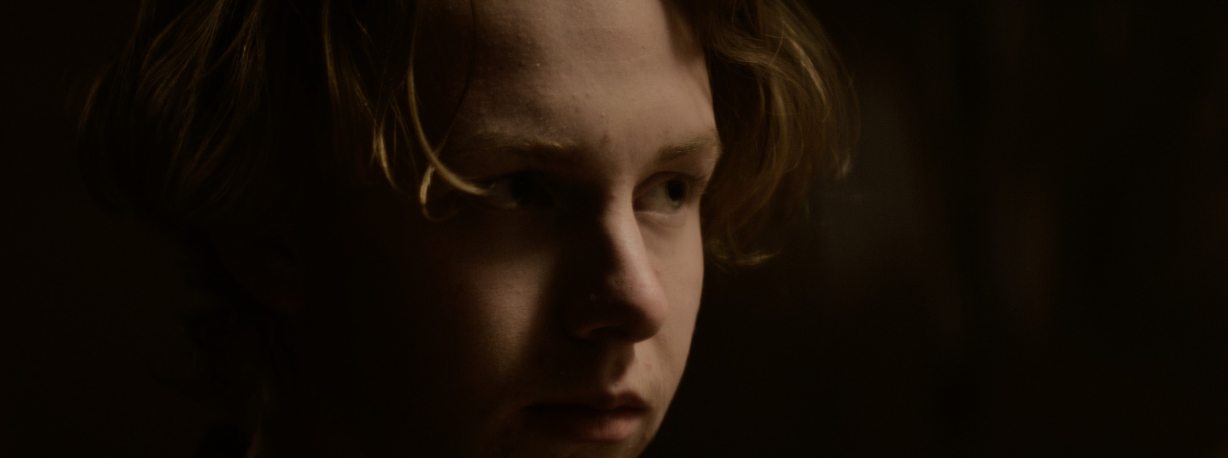 Close-up of a young person in a dark room — Markings of Murder