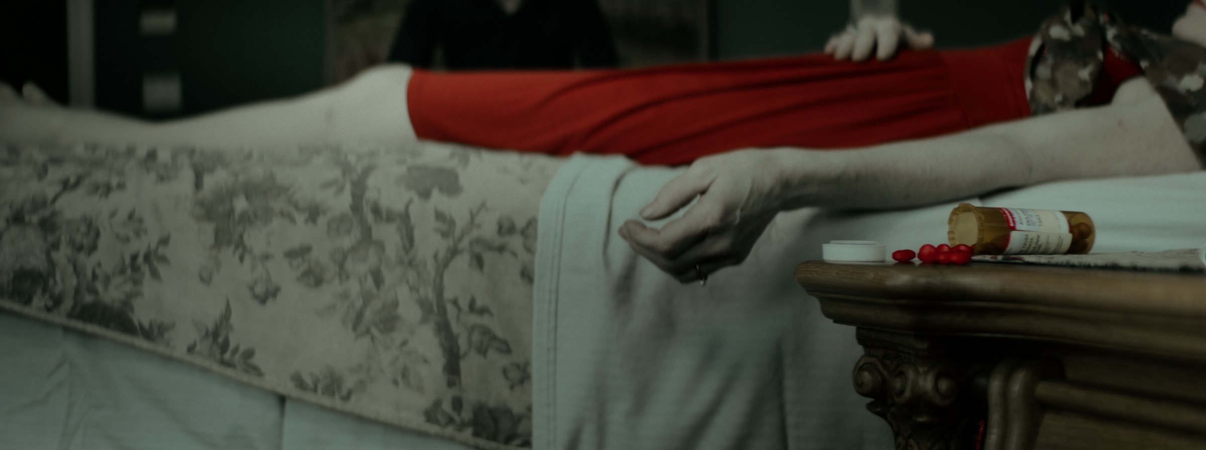 An outstretched arm rests on a floral-covered surface — Markings of Murder