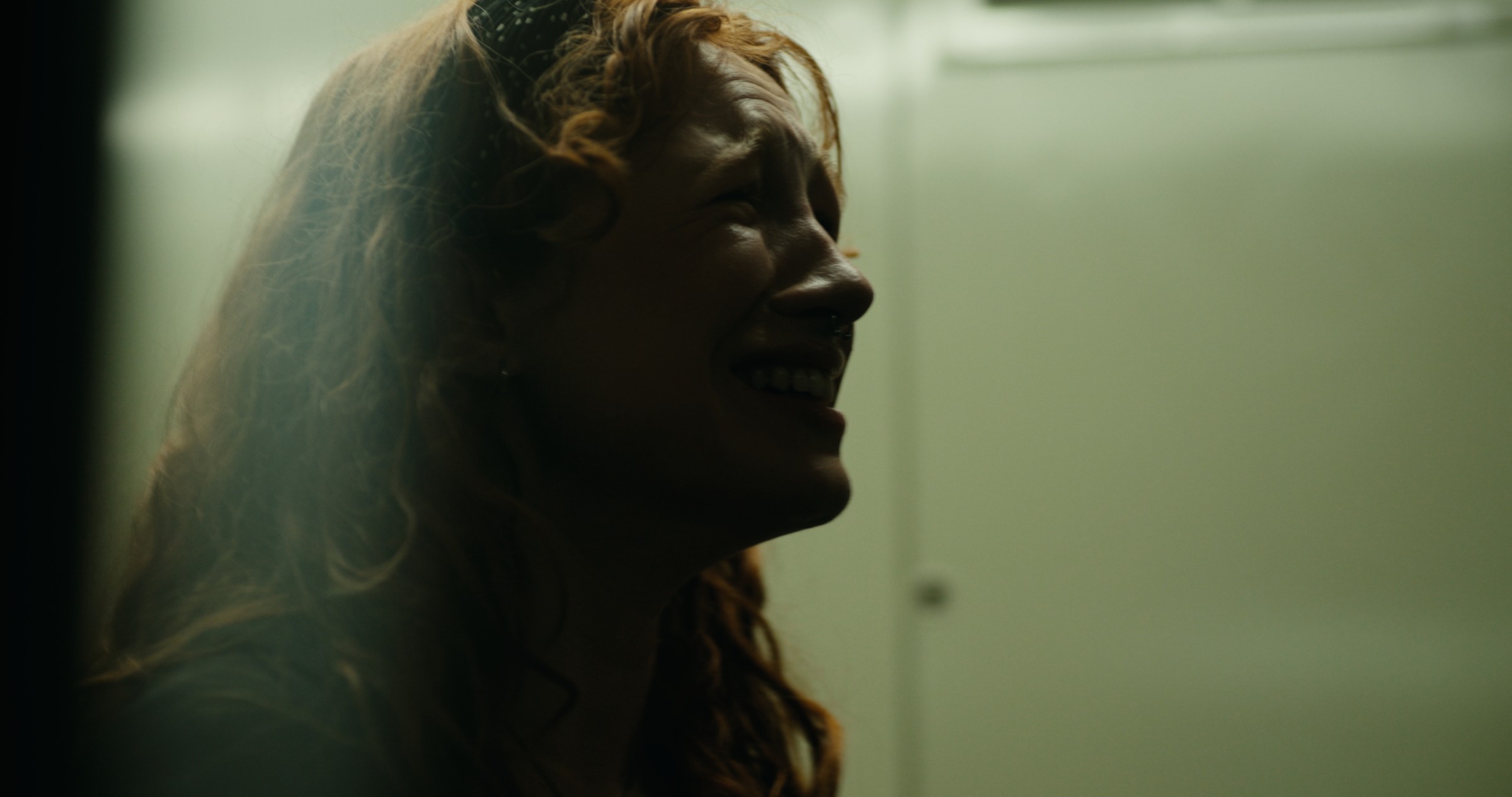 A woman looks up beneath a hazy overhead light — Nemesis