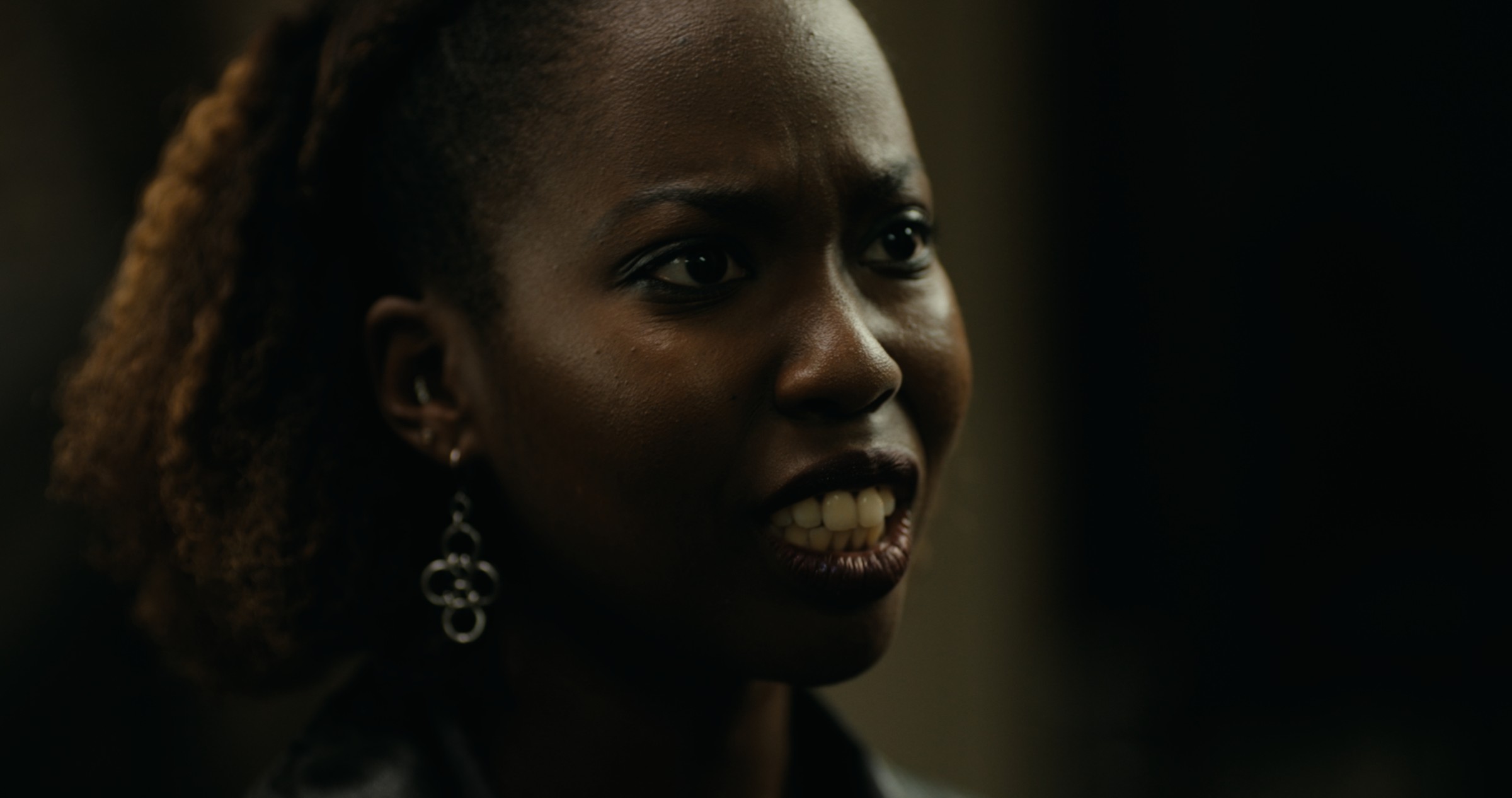 Close-up of a woman speaking in a dark interior — Nemesis