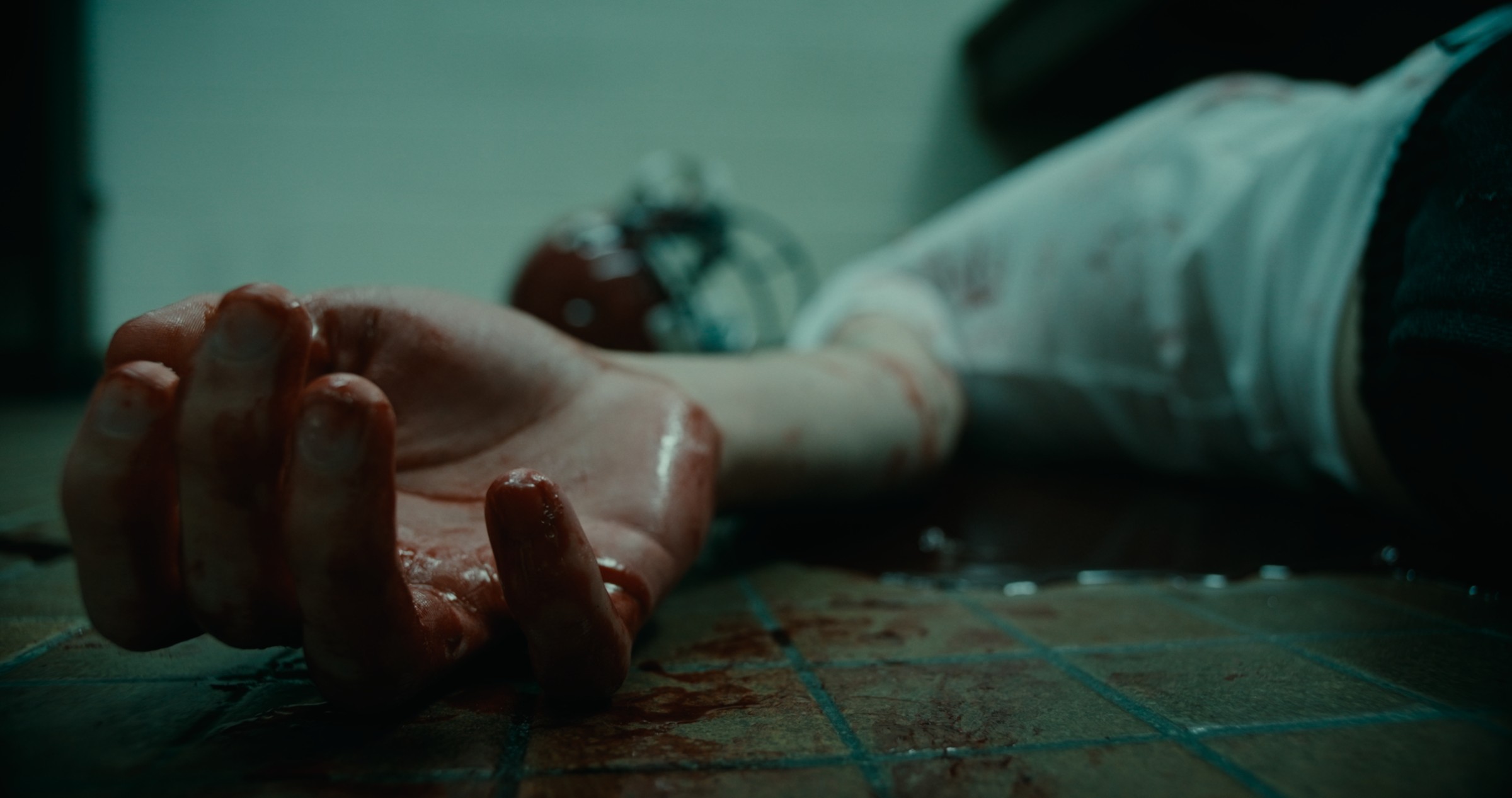 Close-up of an outstretched hand on a tiled floor — Nemesis