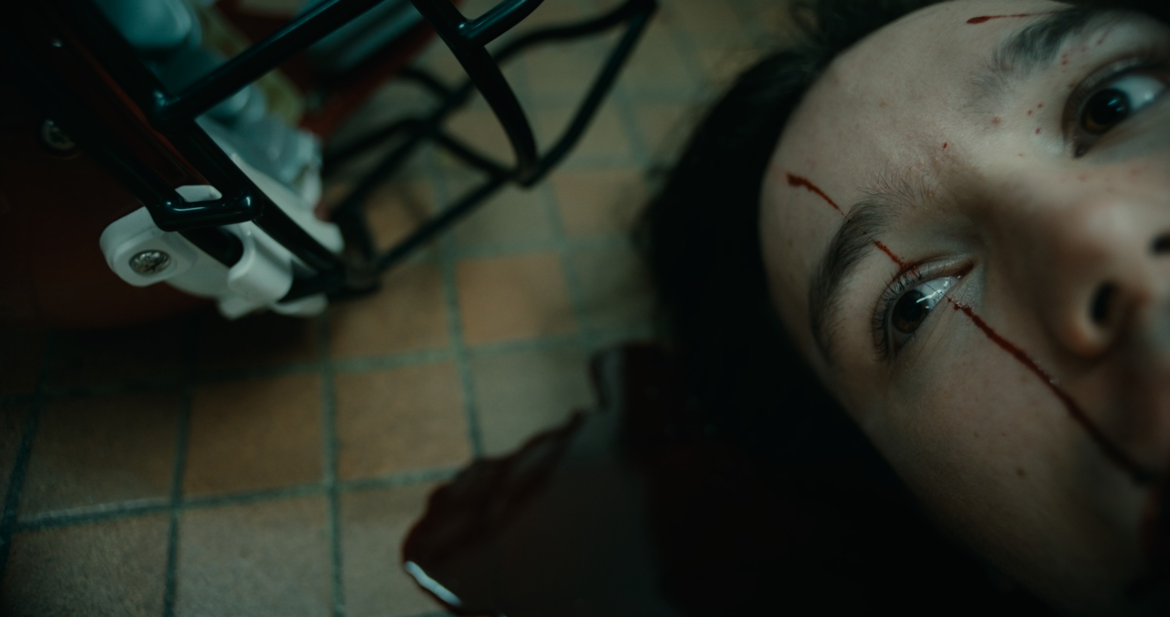 A woman lies on a tiled floor beside a metal device — Nemesis