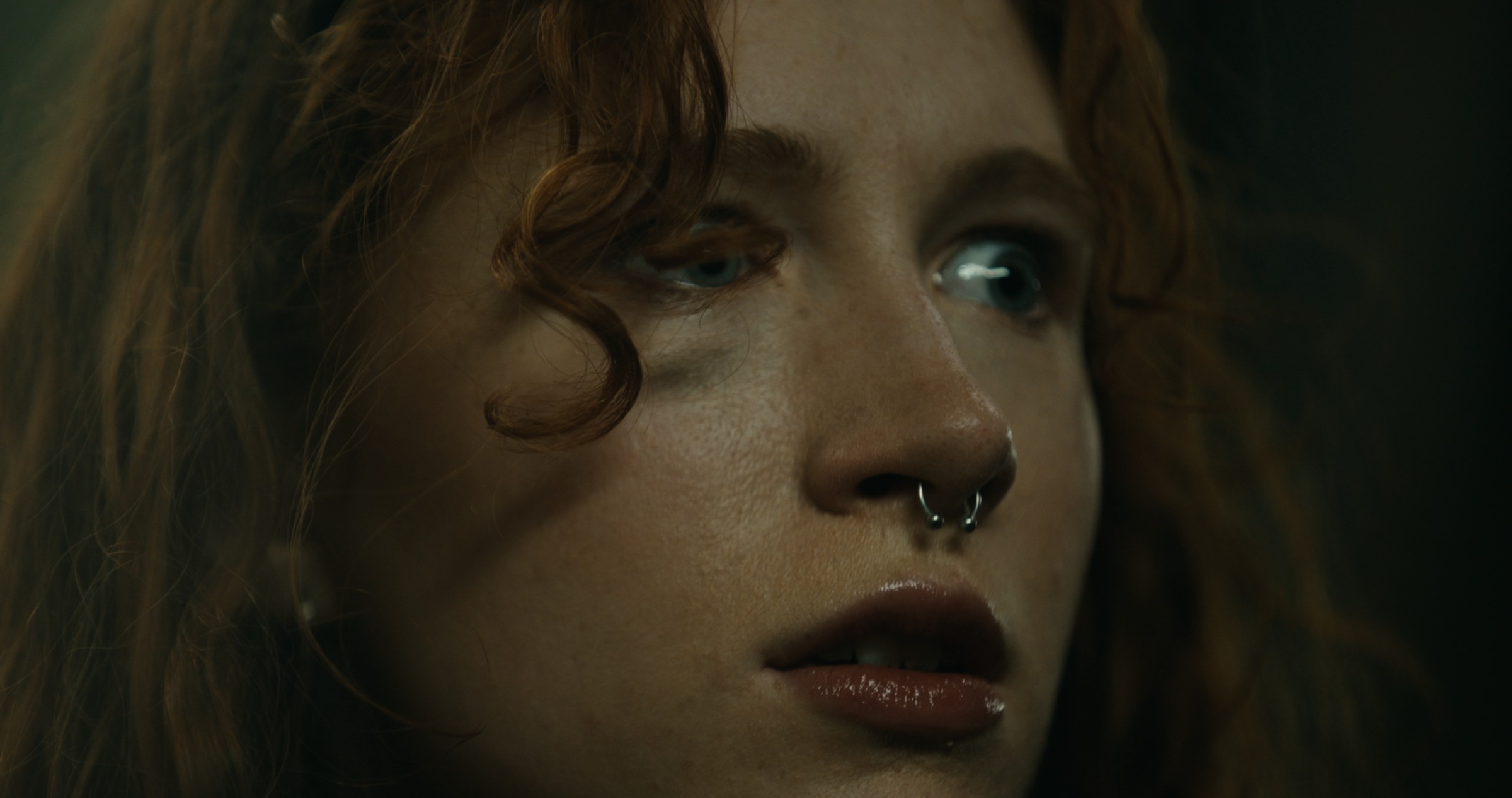 Close-up of a woman's face and nose ring in cool light — Nemesis