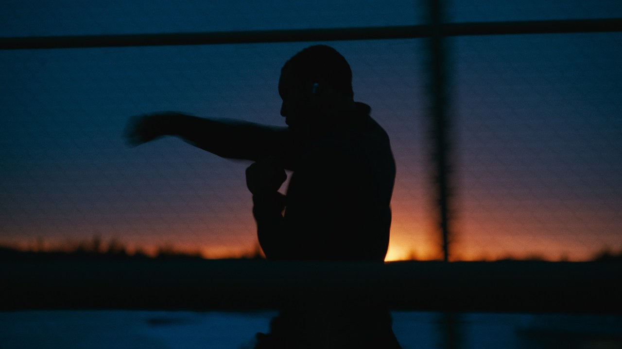 A boxer silhouetted against a blue and orange evening sky in Kinetic