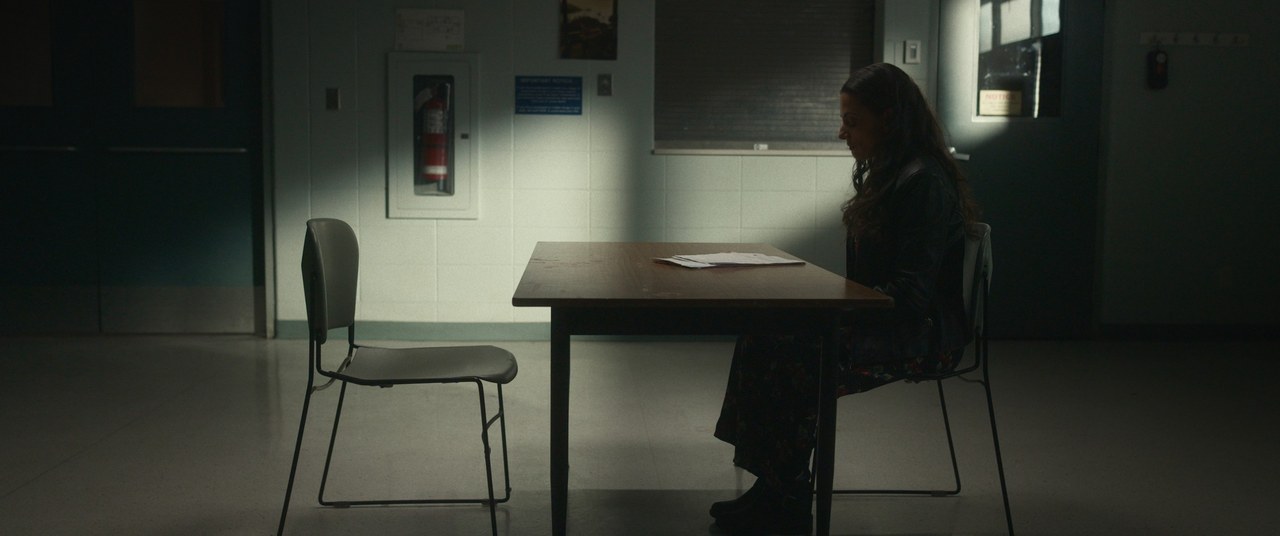 Two women sit across a table in a dim room — The Table Between Us