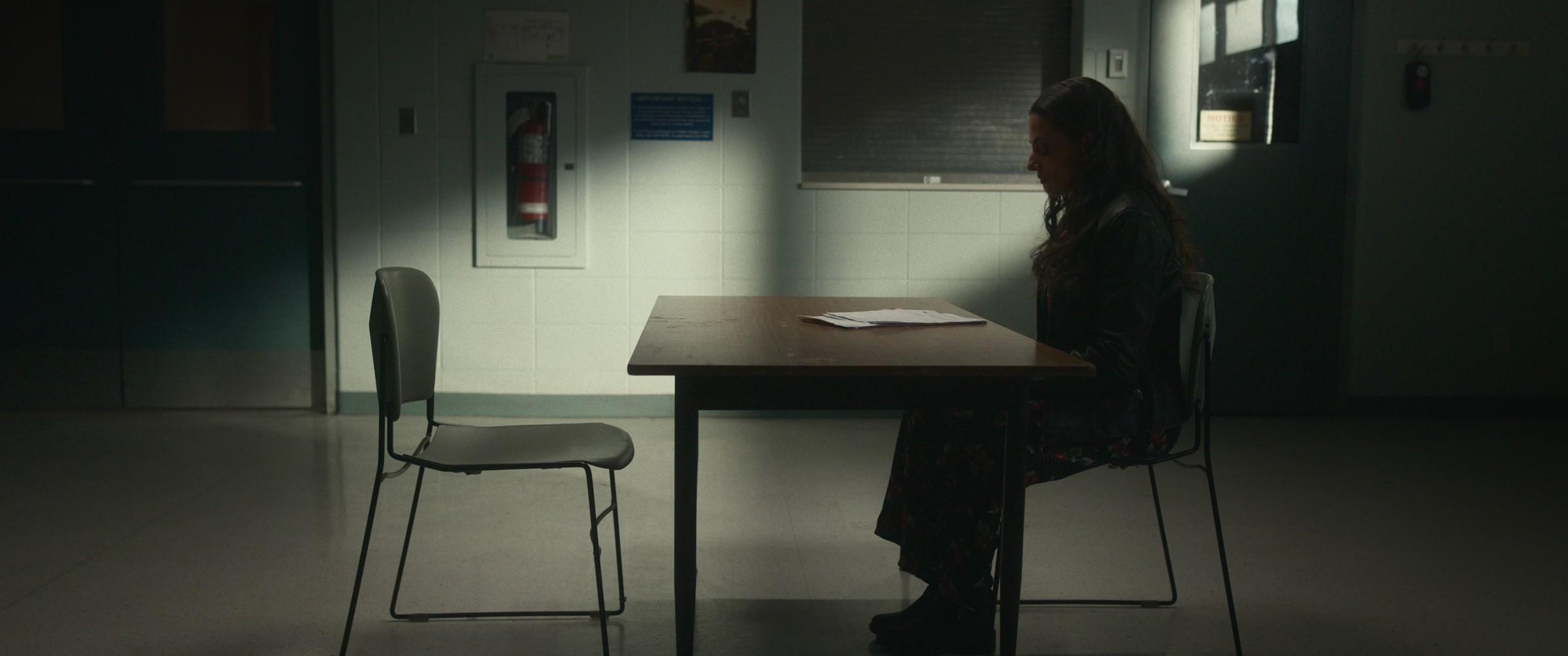 Two women sit across a table in a dim room — The Table Between Us