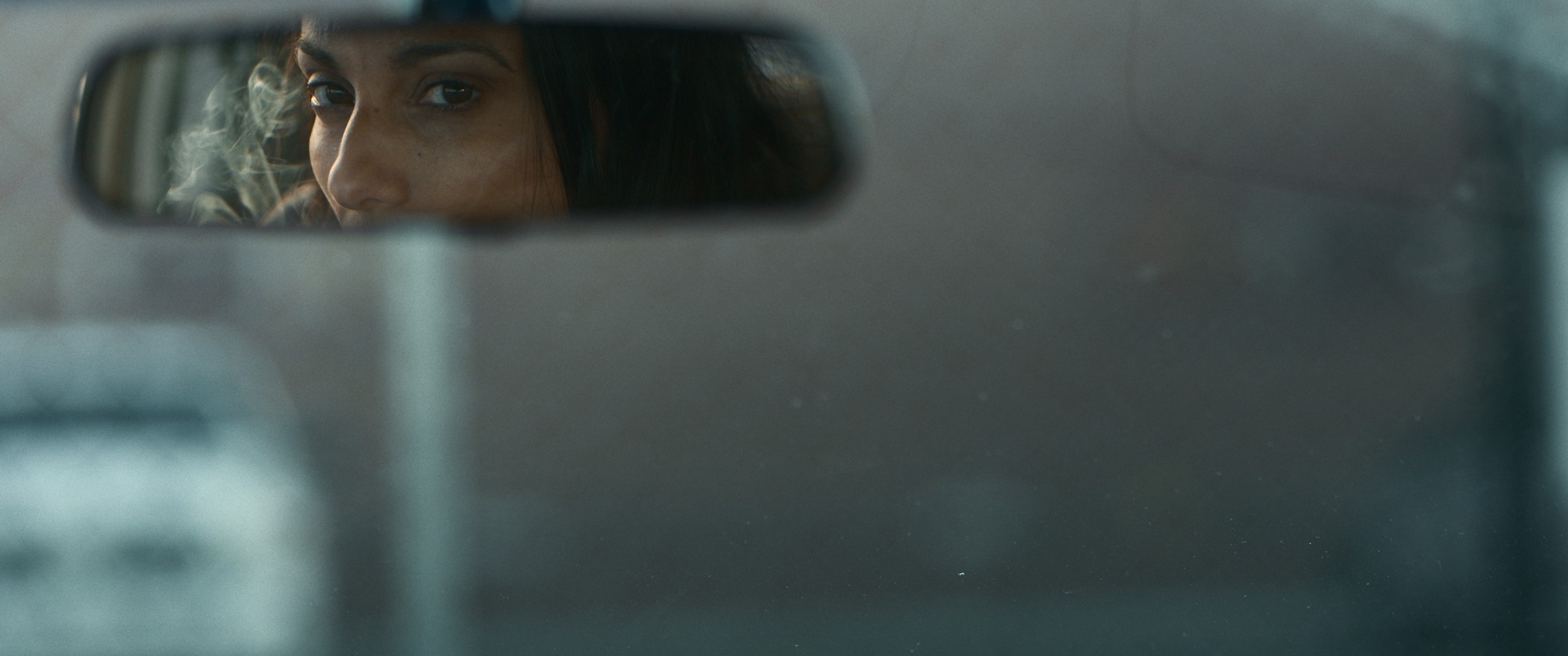 A driver's eyes reflected in a rear-view mirror — The Table Between Us