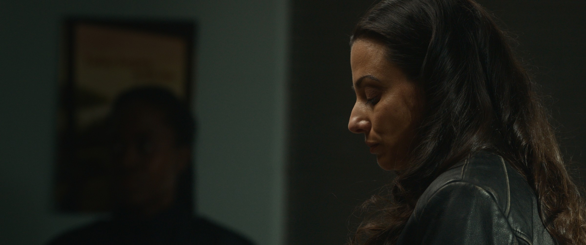 A dark-haired woman looks across a table — The Table Between Us