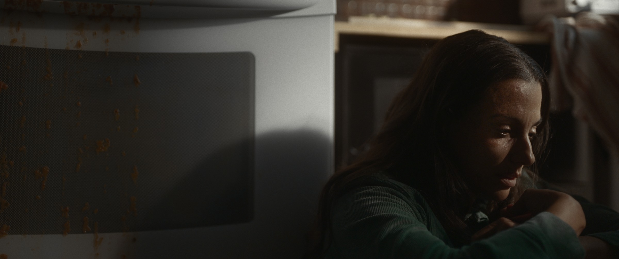 A woman reclines beside a pillow in a dark interior — The Table Between Us