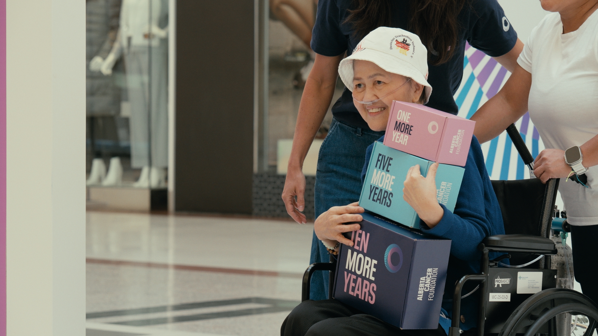 A smiling woman holds colorful boxes while seated in a wheelchair — Time Store